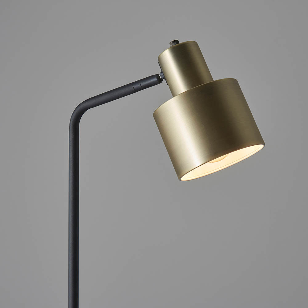 Carlbourne Floor Lamp in brass and black, close-up of the cylindrical brass shade with adjustable black arm, shown against a plain grey background.