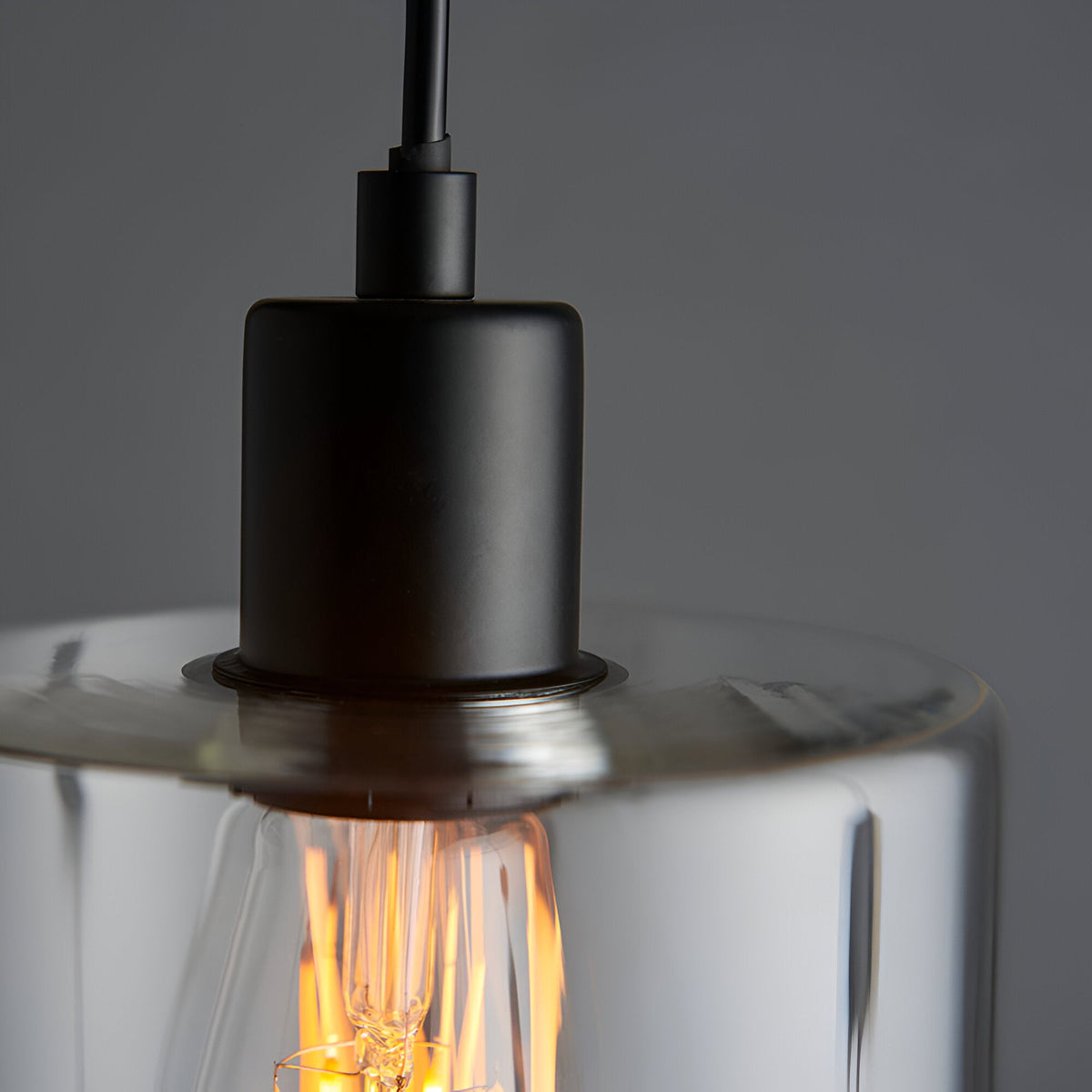 Close-up of the Endon Cranmere pendant light showing the matt black lampholder, black flex, and clear glass shade with a warm filament bulb inside.