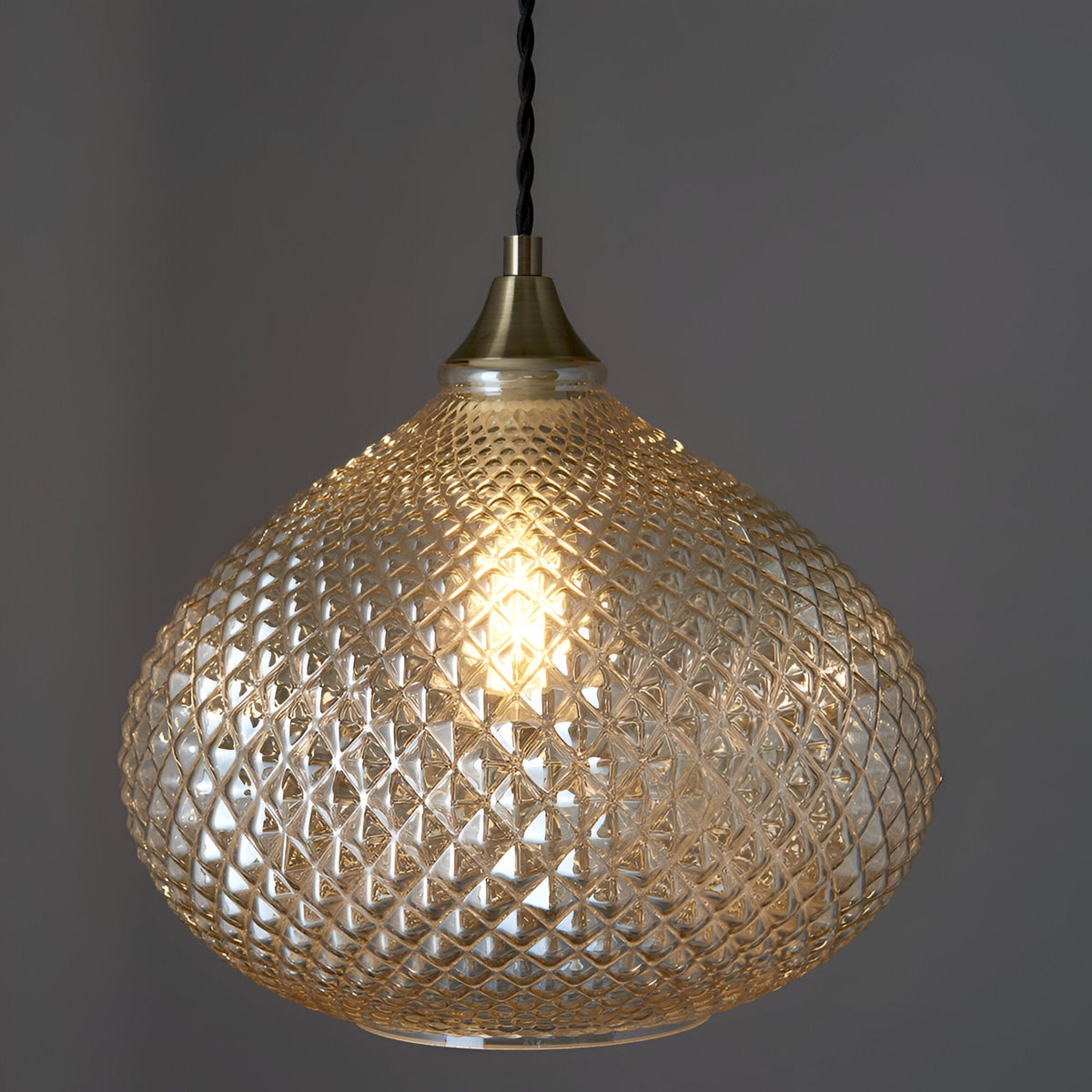 Endon Caldstead pendant light with textured champagne glass shade in an onion silhouette, antique brass fitting, and black twisted fabric flex.