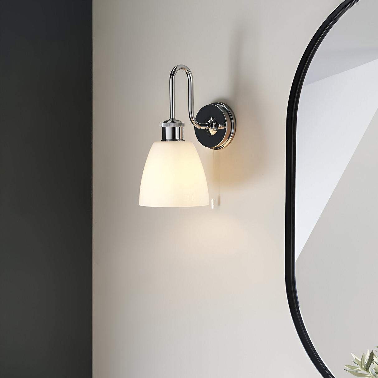 Chartdon bathroom wall light in polished chrome with swan-neck arm, knurled detailing, opal glass shade and pull cord, mounted beside a mirror.