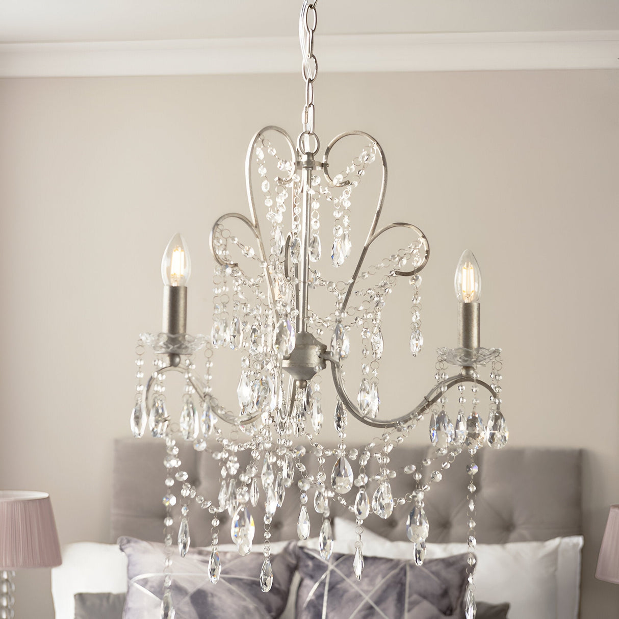 Endon Aldwood 3 light pendant in aged silver with scrolled metal frame and clear faceted crystal droplets, shown above a grey bed.