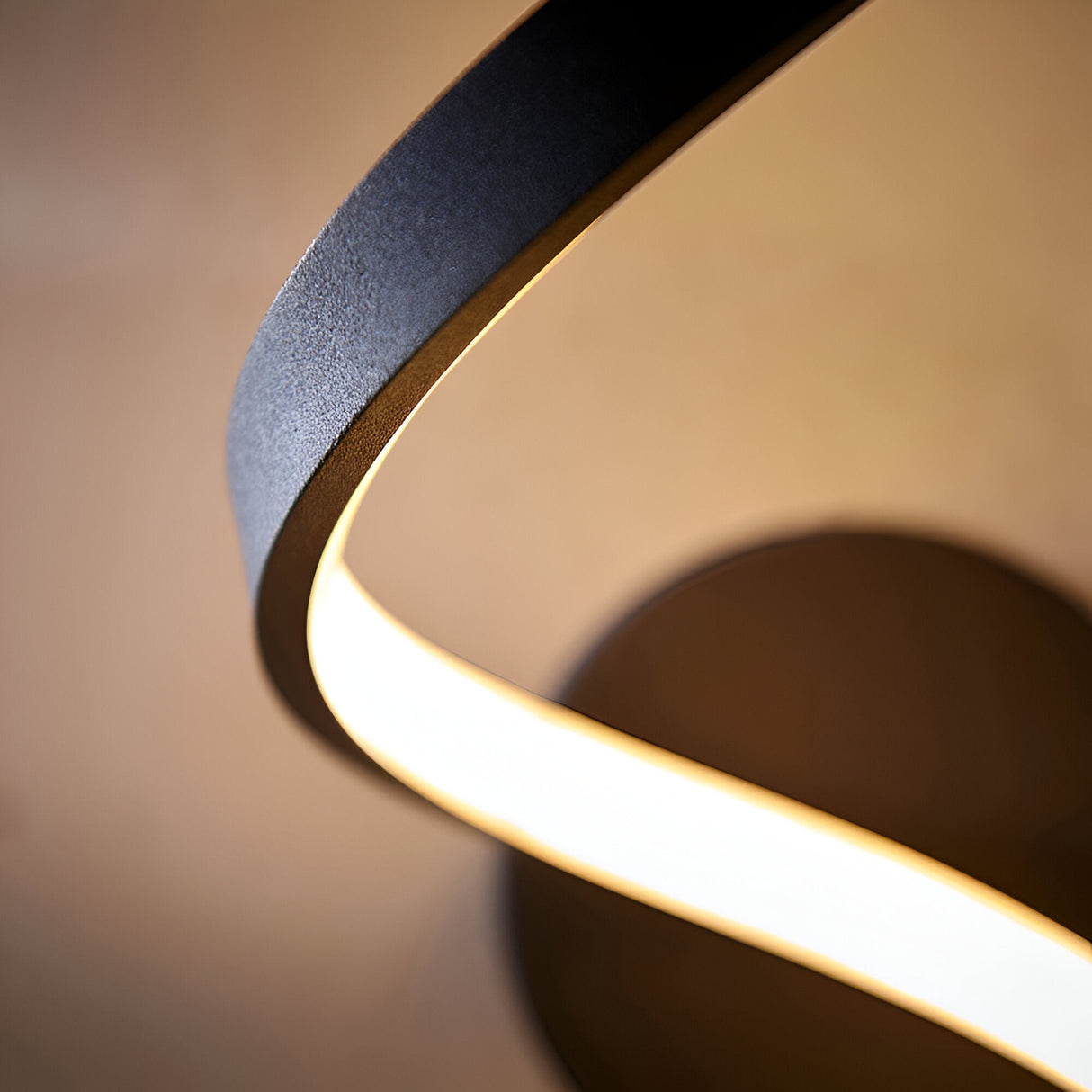 Close-up of the Endon Aldleigh LED wall light showing its twisting textured black form with a warm white illuminated edge.