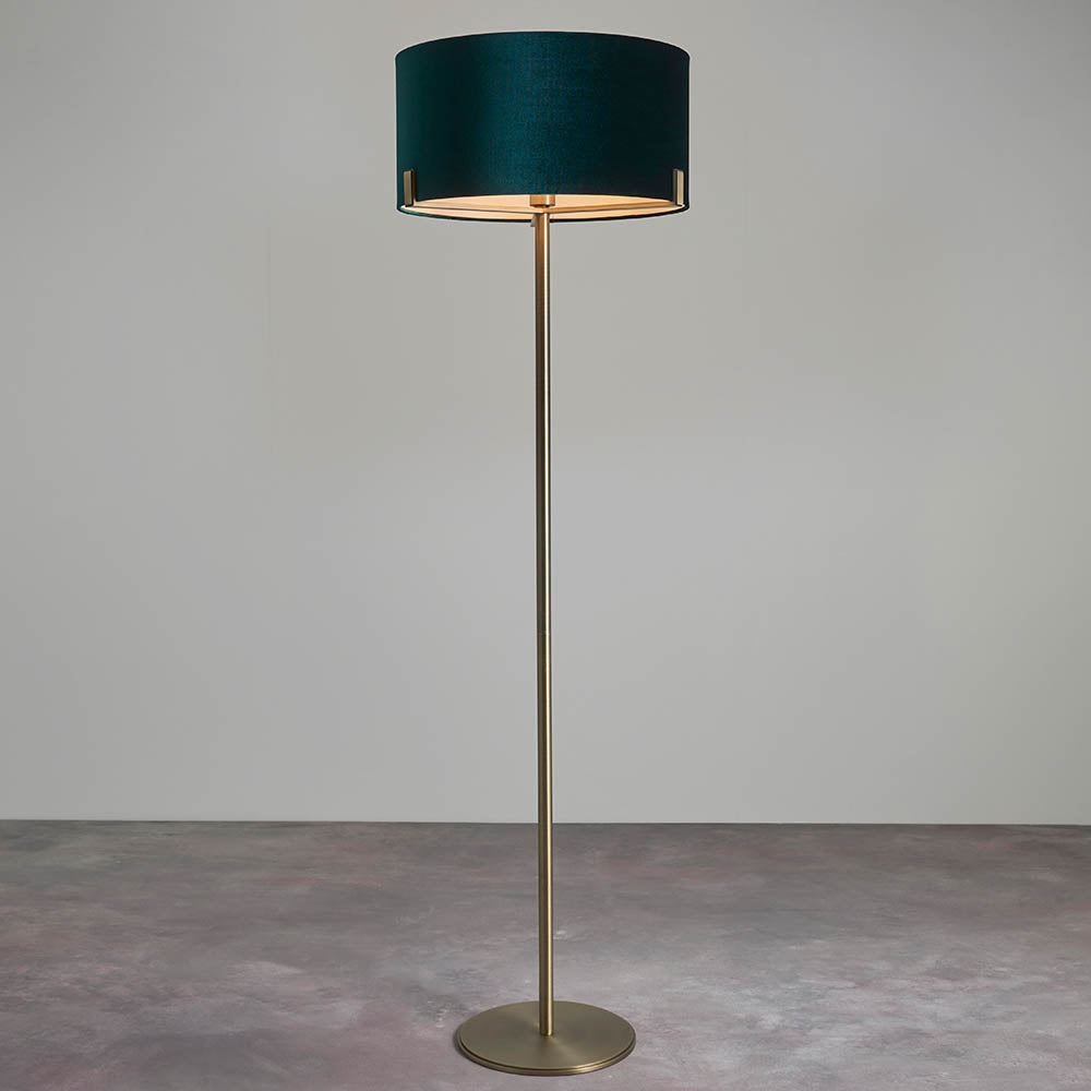 Endon Brendon floor lamp with slim antique brass stand, round base and green velvet cylinder shade, shown against a plain light background.