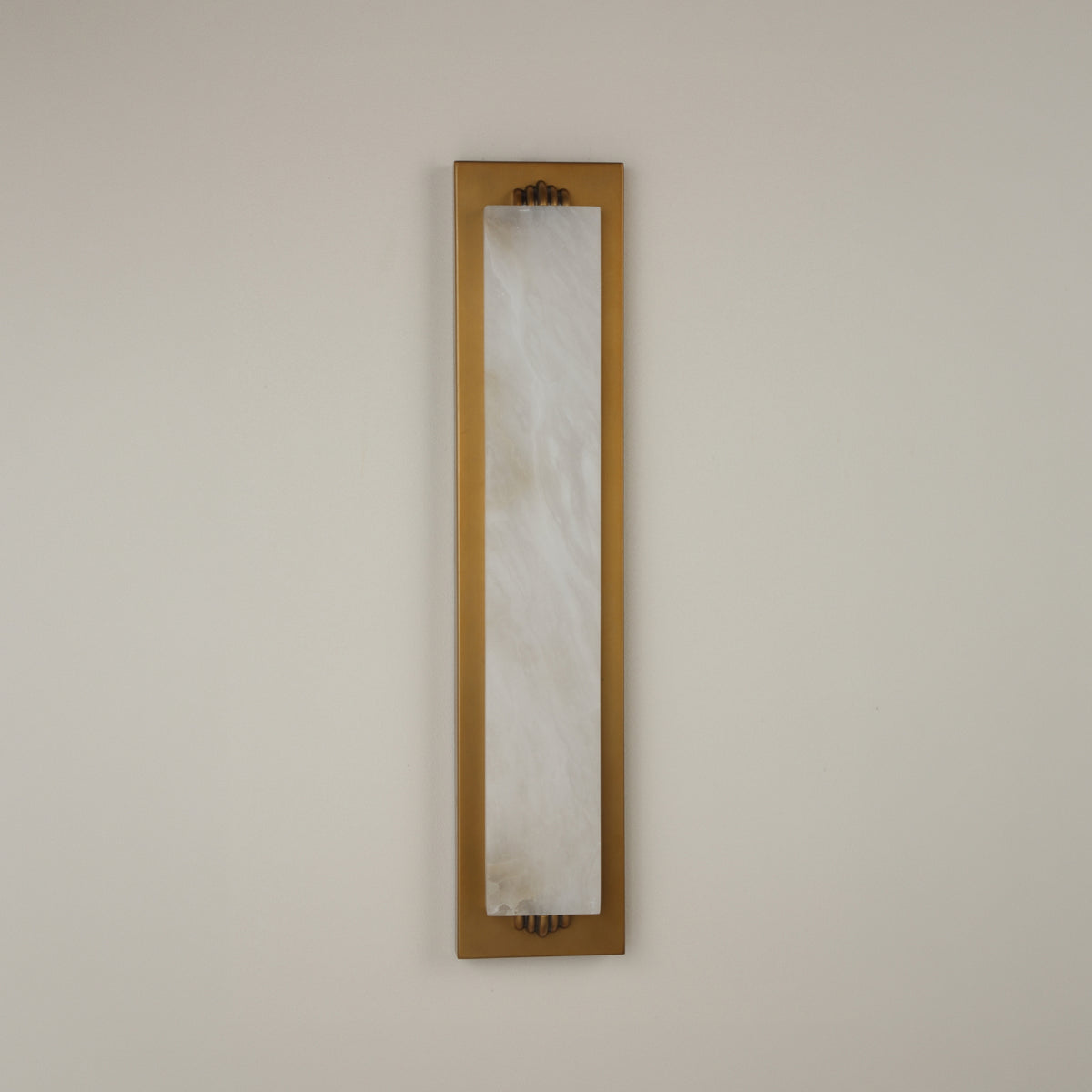 Valora vertical wall light with a tall natural alabaster panel in a brushed brass rectangular frame, mounted on a plain light background.