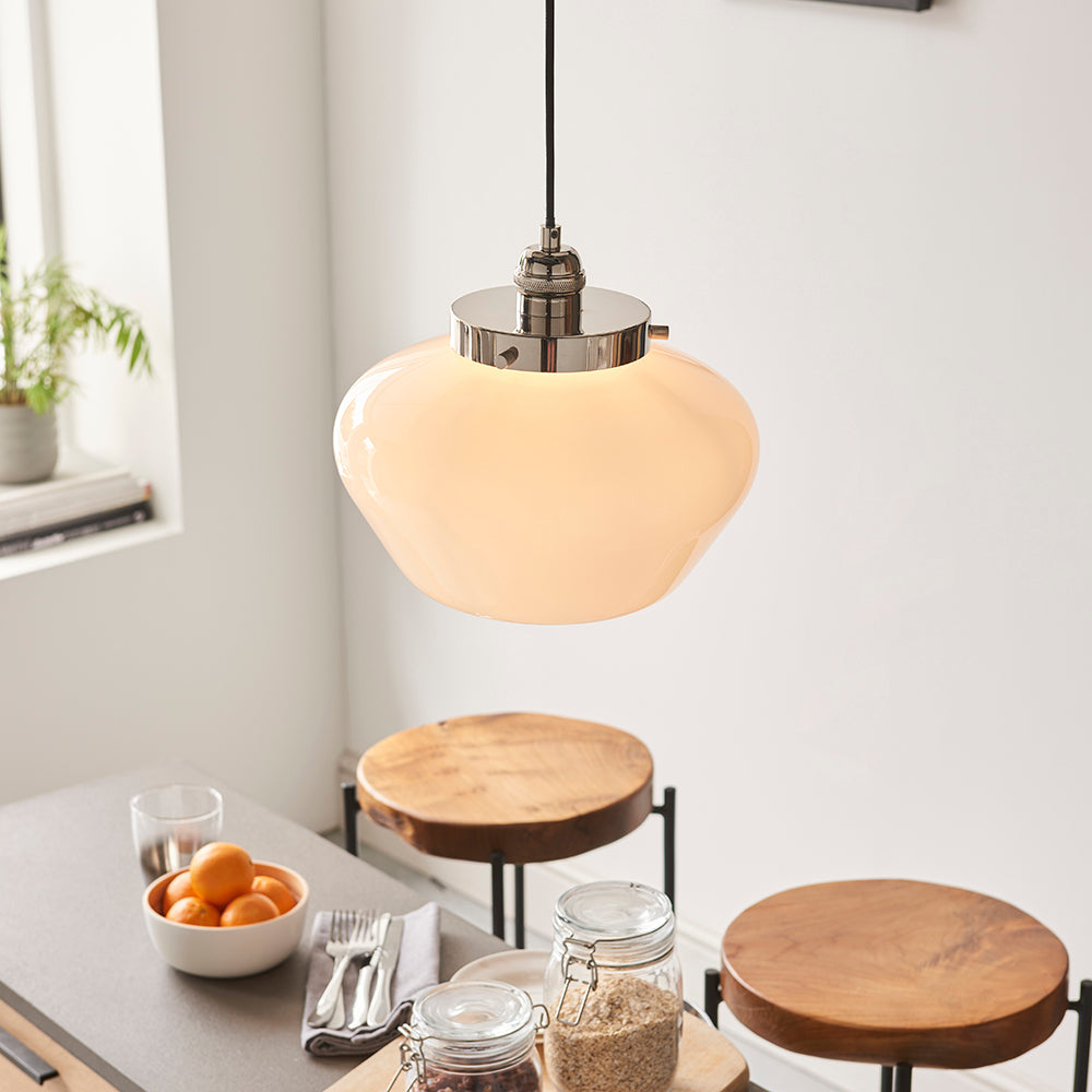 Endon Kedleston pendant light with rounded opal glass shade and polished nickel fitting on black flex, hung above a kitchen table with fruit bowl and stools.