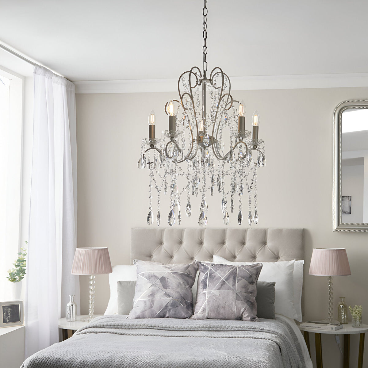 Endon Aldwood 5 light pendant in aged silver with faceted crystal droplets, hung above an upholstered bed with pink shaded lamps in a neutral bedroom.