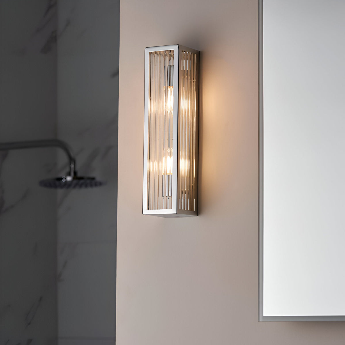 Endon Castcombe 2 light bathroom wall light in chrome with ribbed glass diffuser, mounted on a neutral wall beside a mirror and shower.