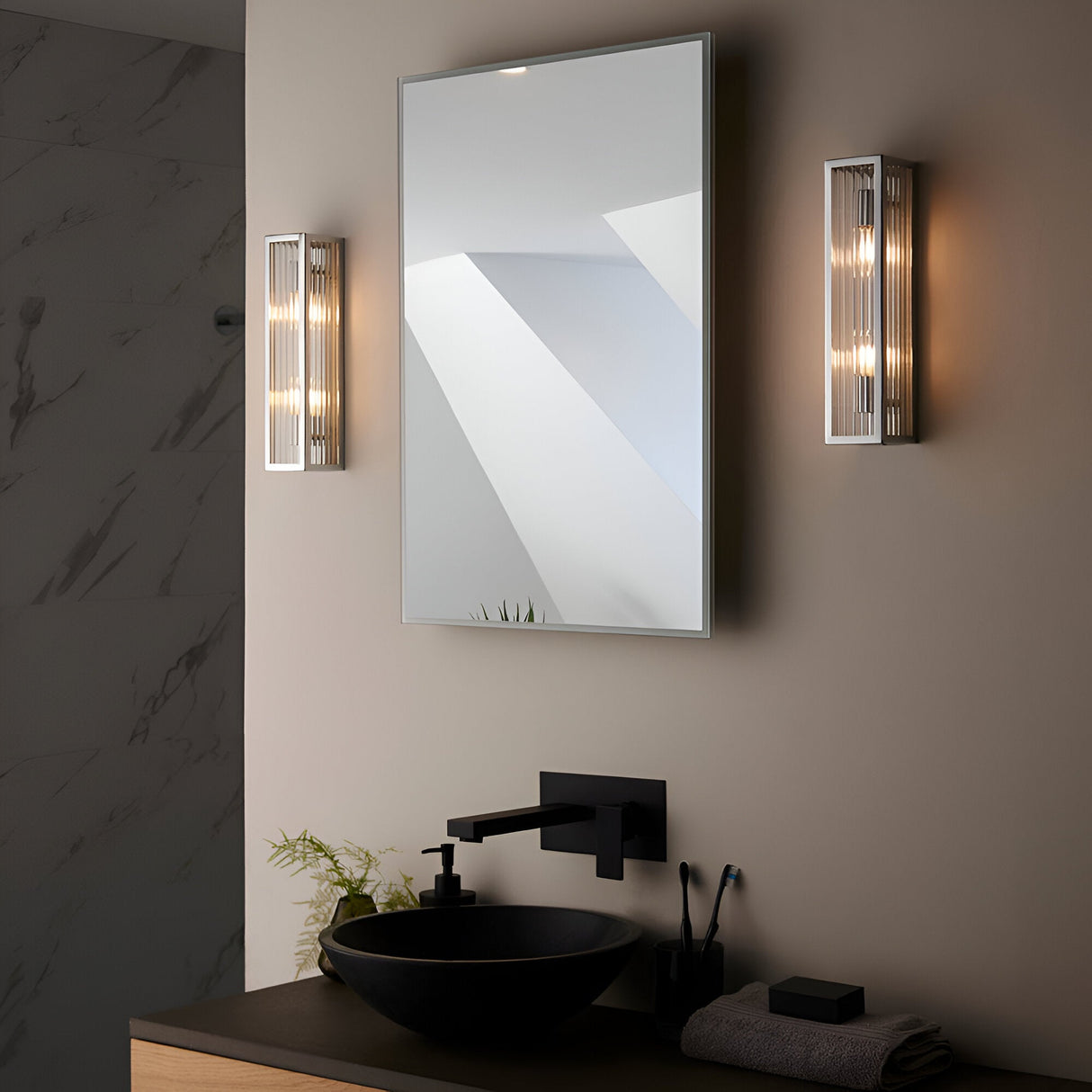 Endon Castcombe 2 light bathroom wall lights in chrome with ribbed glass diffusers, mounted either side of a rectangular mirror above a black vessel sink.