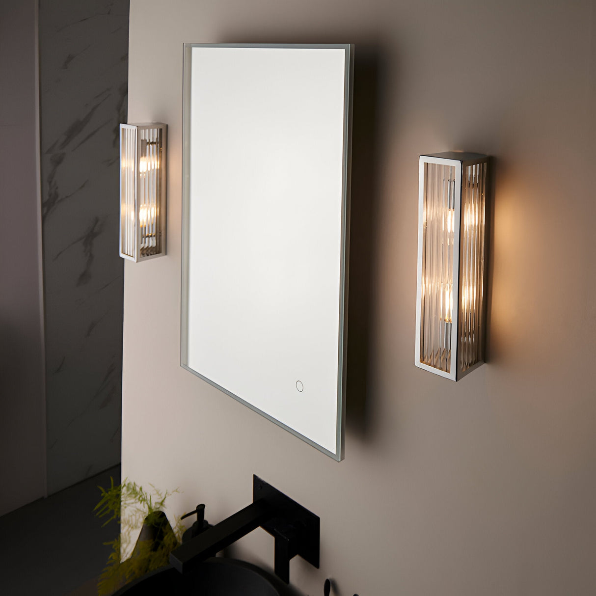 Endon Castcombe 2 light bathroom wall lights in chrome with ribbed glass diffusers, flanking an illuminated rectangular mirror above a black basin.