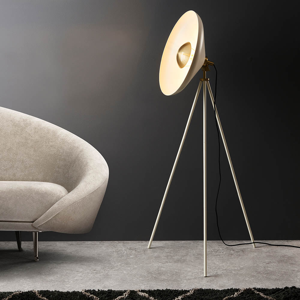 Endon Bramshaw Floor Lamp in white with brushed brass details, tripod stance and tilted dish shade, shown beside a cream sofa in a living room.