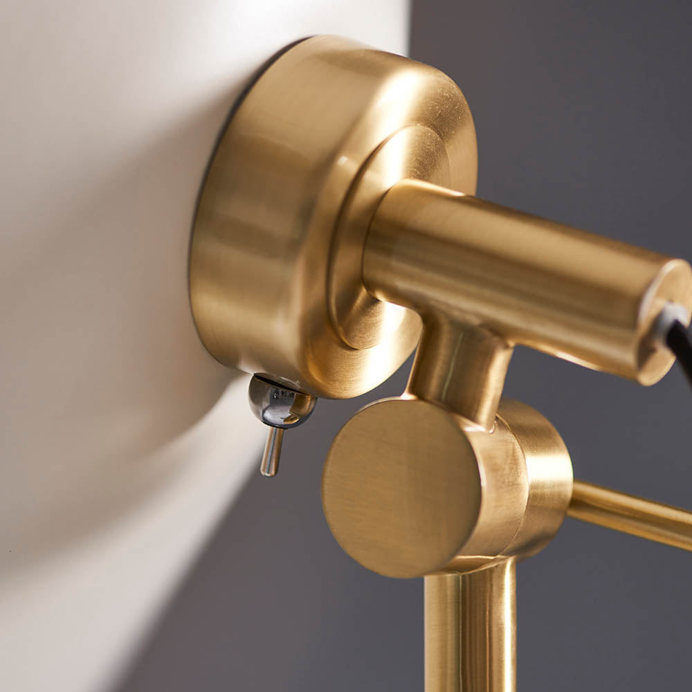 Close-up of the Endon Bramshaw Floor Lamp's brushed brass tilt joint and cylindrical head against a white shade and grey background.