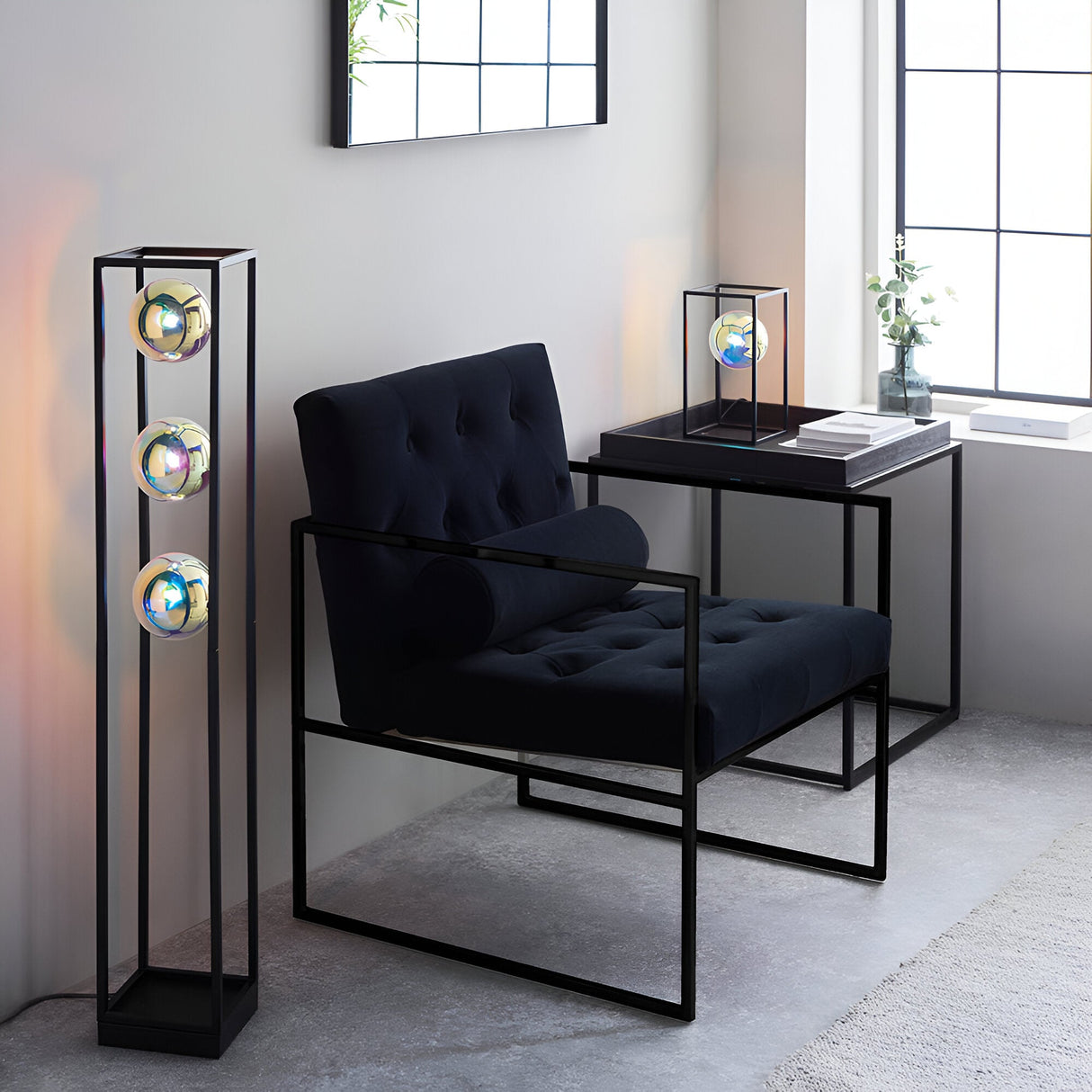 Brockwell Table Lamp in matt black open-frame design with iridescent orb glass shade, shown on a side table in a living room setting.