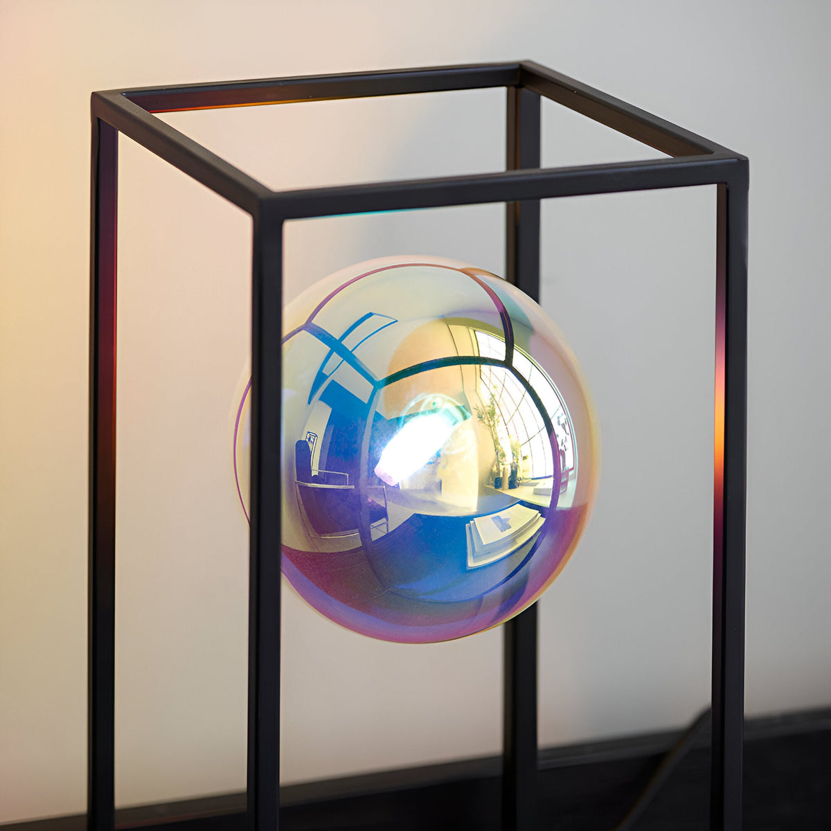Brockwell Table Lamp in matt black, open cube frame with an iridescent orb glass shade suspended inside, set against a plain light background.
