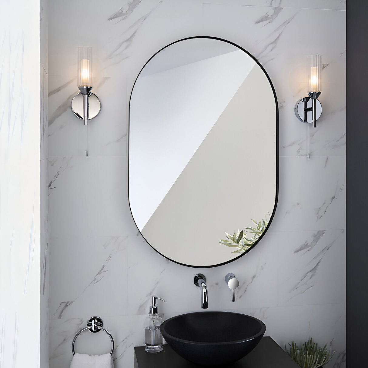 Endon Castbourne chrome bathroom wall lights with ribbed glass shades flanking an oval black-framed mirror above a black vessel sink on marble.