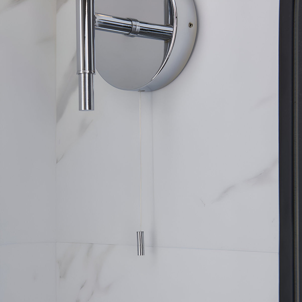 Endon Castbourne bathroom wall light in polished chrome with upward torch shade, circular back plate and pull cord switch, mounted on a marble wall.