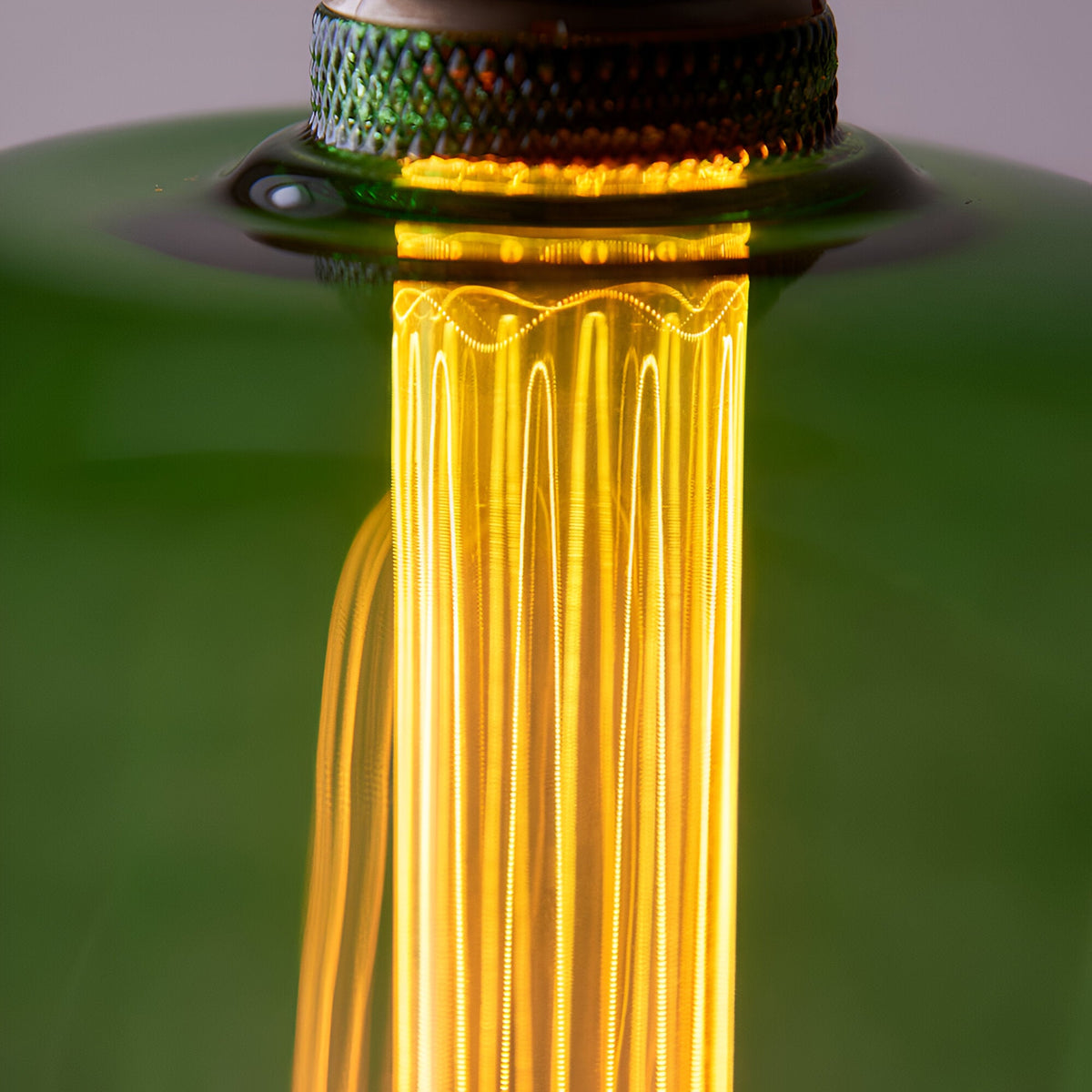 Close-up of Endon 2.8W E27 LED filament bulb showing the etched acrylic diffuser sleeve glowing warm amber inside the green-tinted glass.