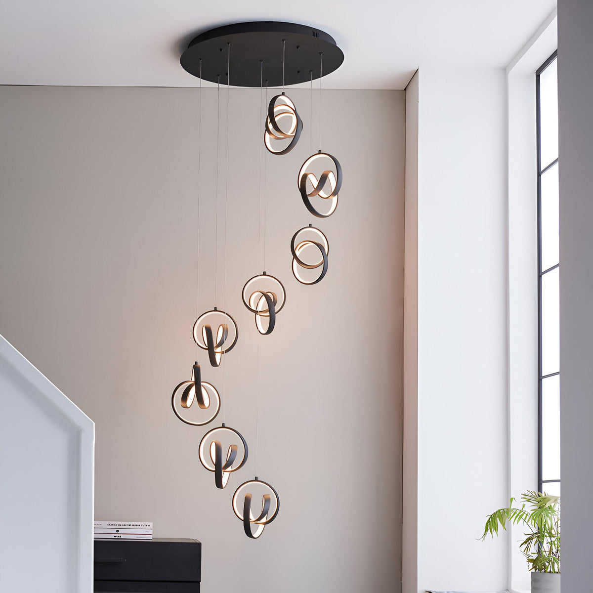Endon Bevwell 8 light pendant in matt black, with swirling looped LED rings cascading in a spiral drop in a bright modern stairwell.