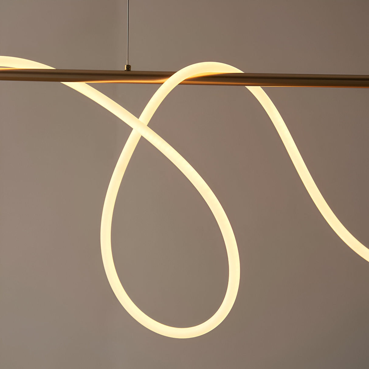 Aldley Linear Pendant in satin gold, showing the flexible LED tube curved into loops beneath the linear bar, set against a plain grey background.