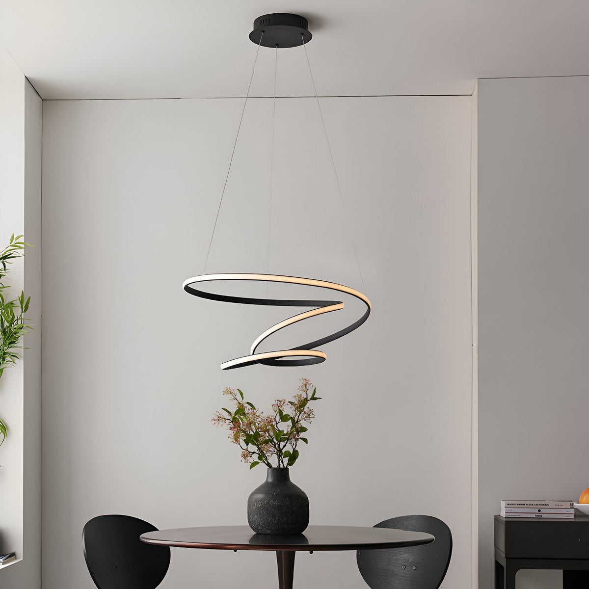 Endon Halden pendant light with a swirling ribbon-style LED loop in matte black, suspended from a round ceiling plate above a dining table.