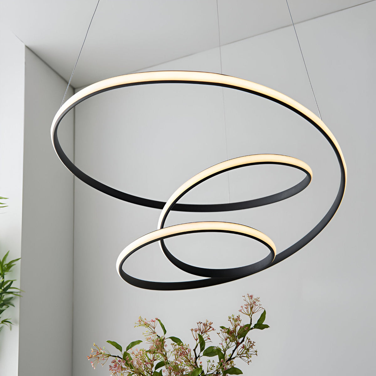 Endon Halden pendant light with three interlocking textured black rings and warm integrated LED diffusers, suspended in a modern white interior.