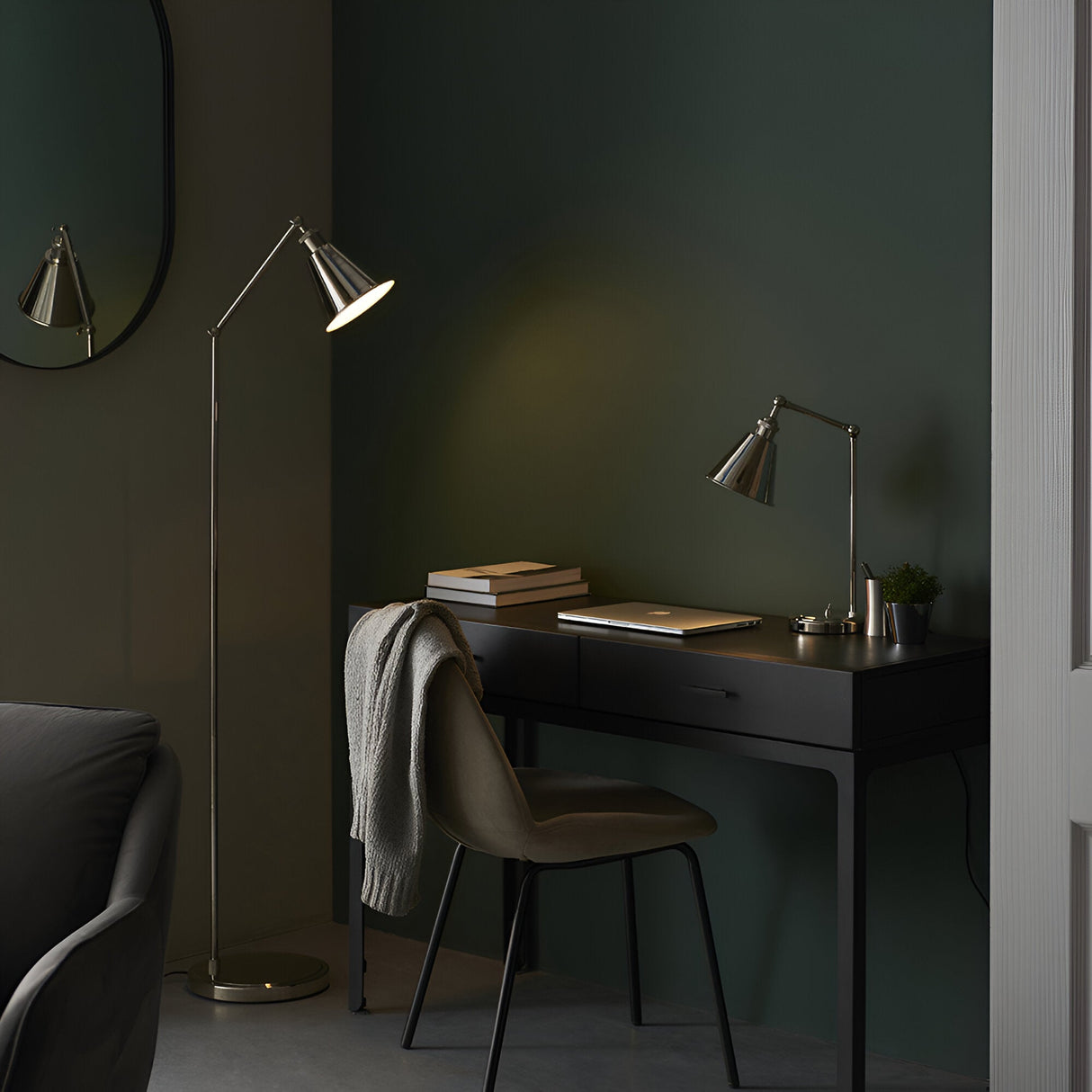 Endon Brackley nickel floor lamp with adjustable arm and conical shade beside a black desk and chair in a dark green bedroom workspace.