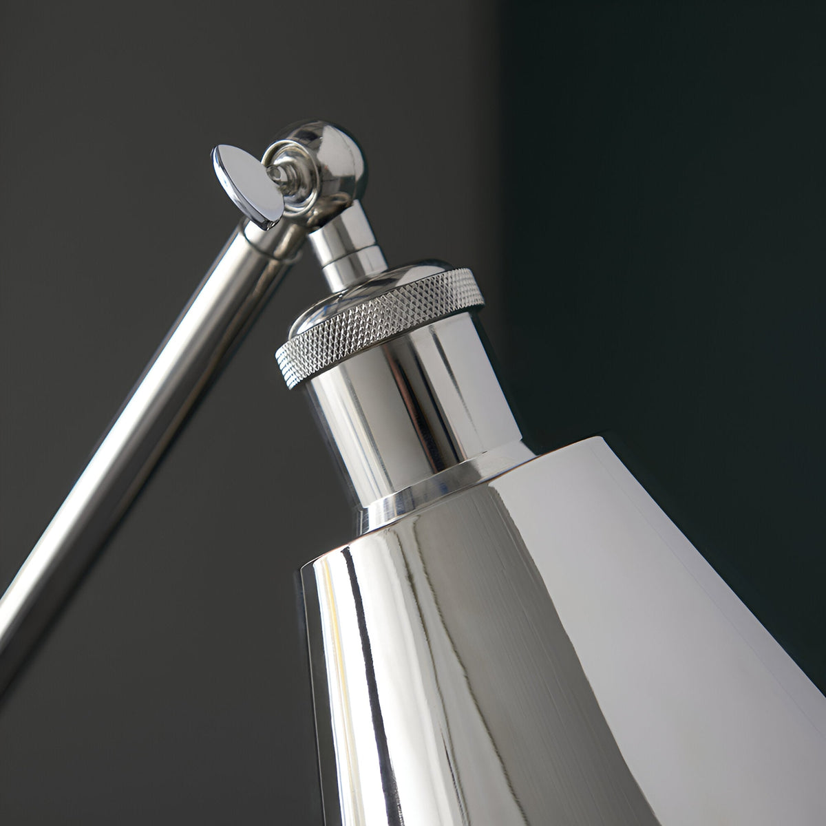 Close-up of the Endon Brackley floor lamp head and adjustable arm joint in bright nickel plate with knurled detailing against a dark background.