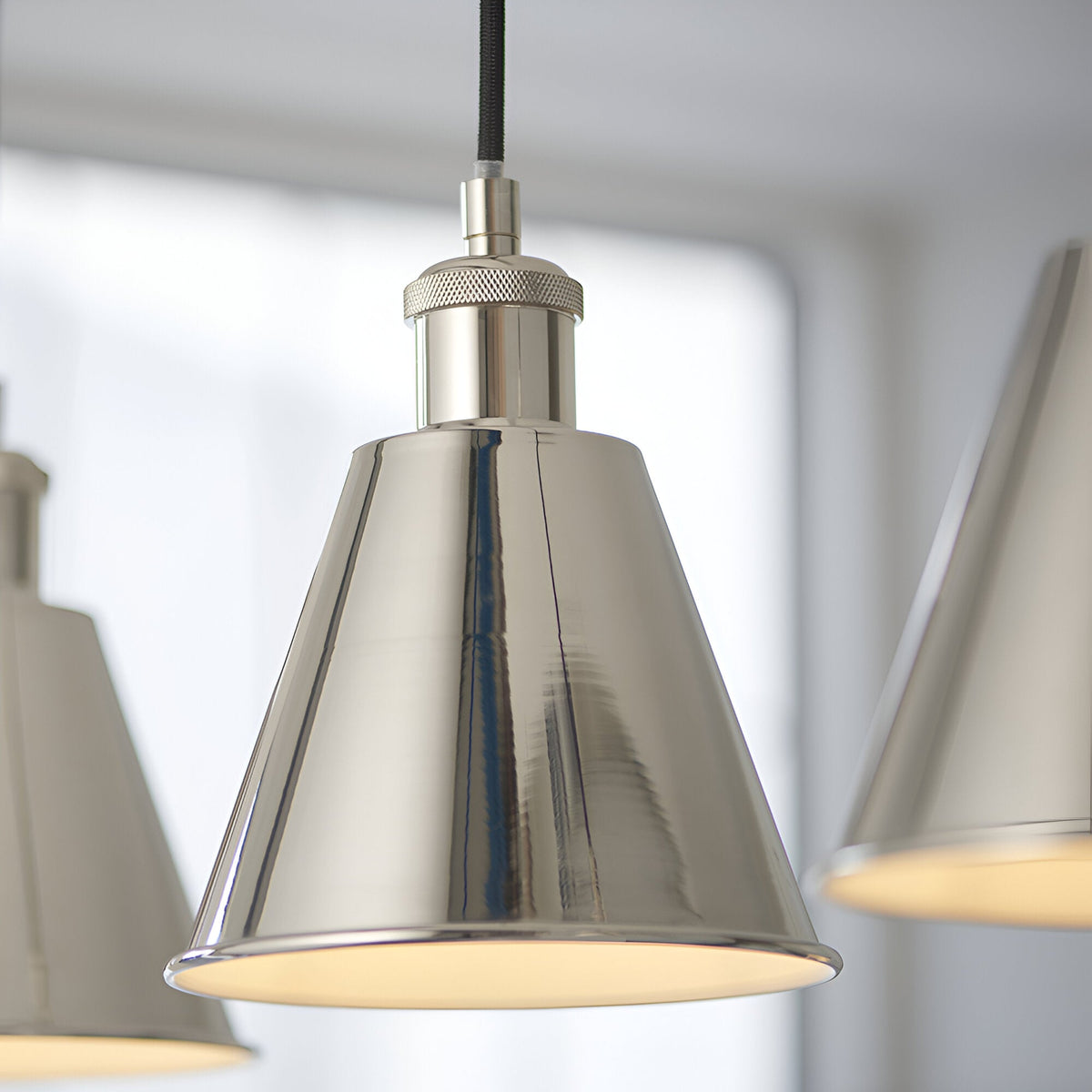Close-up of the Endon Brackley pendant light showing a polished nickel conical shade with knurled collar detail, black fabric flex, and white inner.