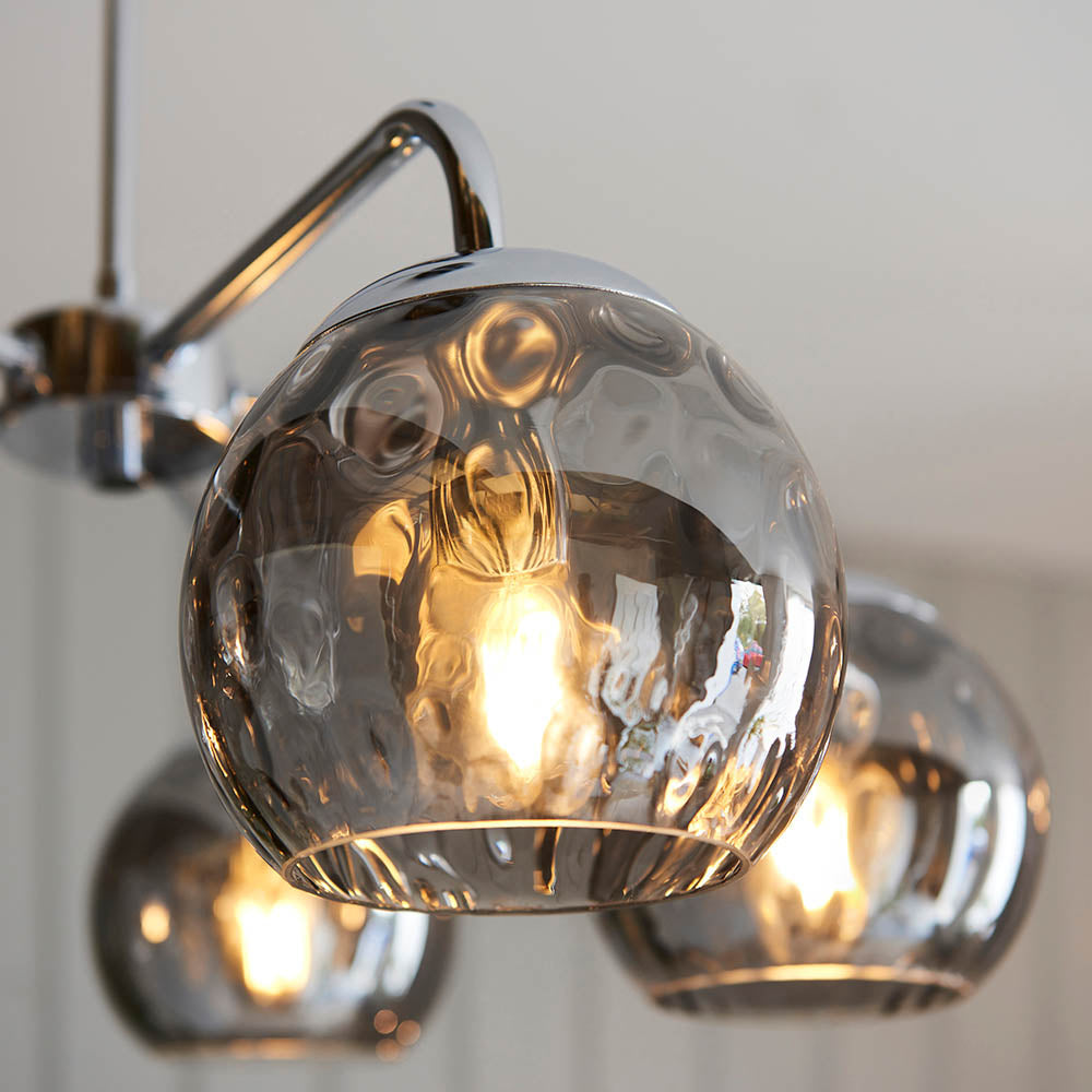 Draycott 5 Light Dimpled Glass Pendant in Chrome, close-up of smokey mirrored glass globe shades with visible bulbs and chrome arm fittings.