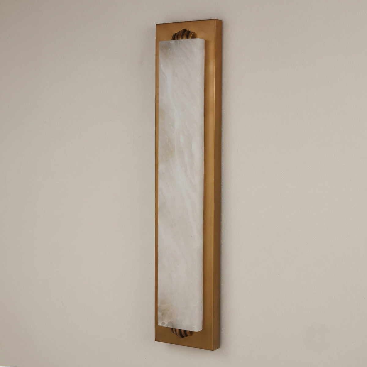 Valora vertical wall light with tall natural alabaster panel in a brushed brass rectangular frame, mounted on a plain light wall.