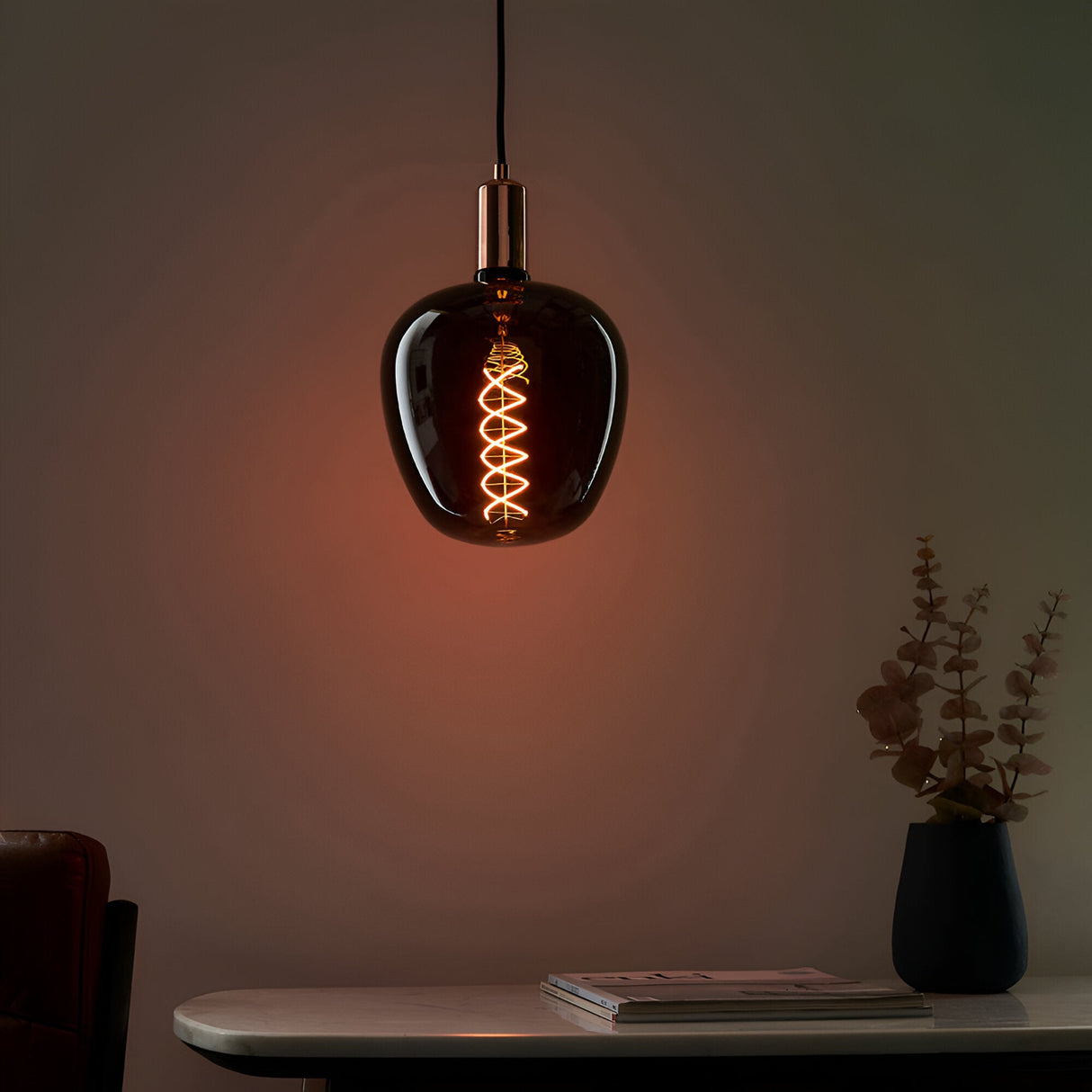 Endon 4W E27 LED filament helix bulb in smoked glass with warm white spiral filament, shown lit in a copper pendant holder above a marble console table.