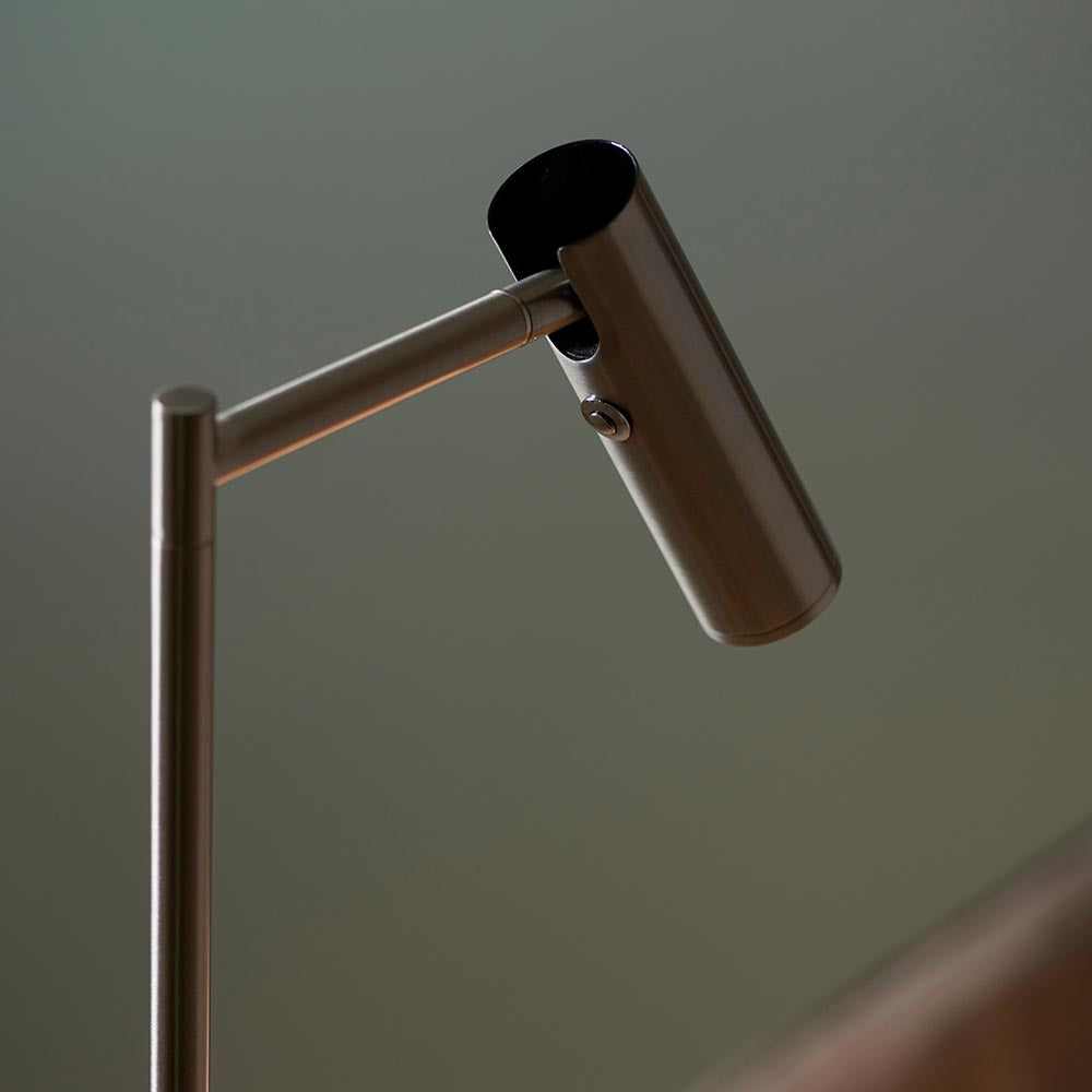 Close-up of the Endon Brackbourne floor lamp's satin nickel cylindrical head and adjustable arm against a soft green background.