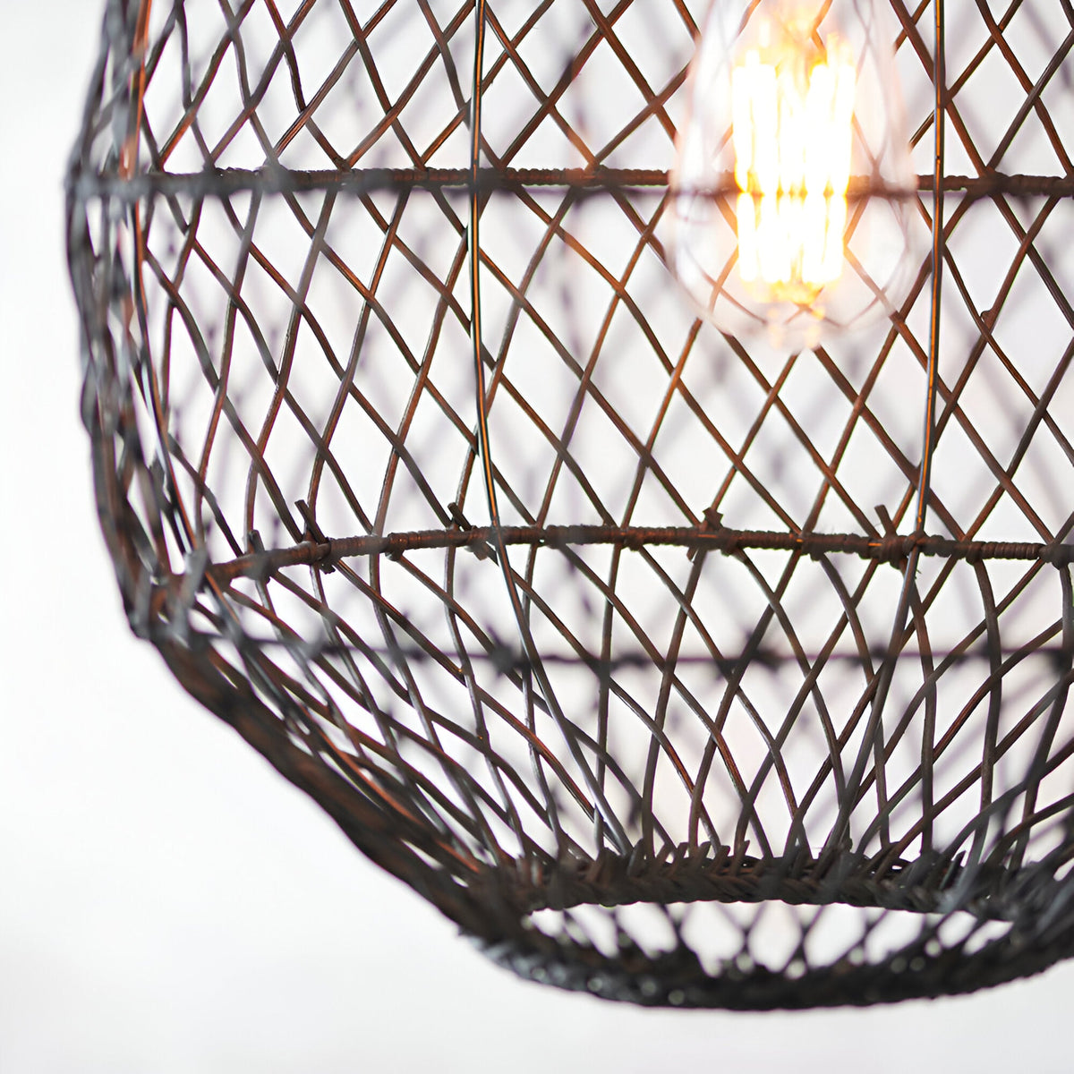 Close-up of the Endon Chartdale pendant showing its hand-woven black rattan shade in an open diamond weave with a lit E27 filament bulb inside.