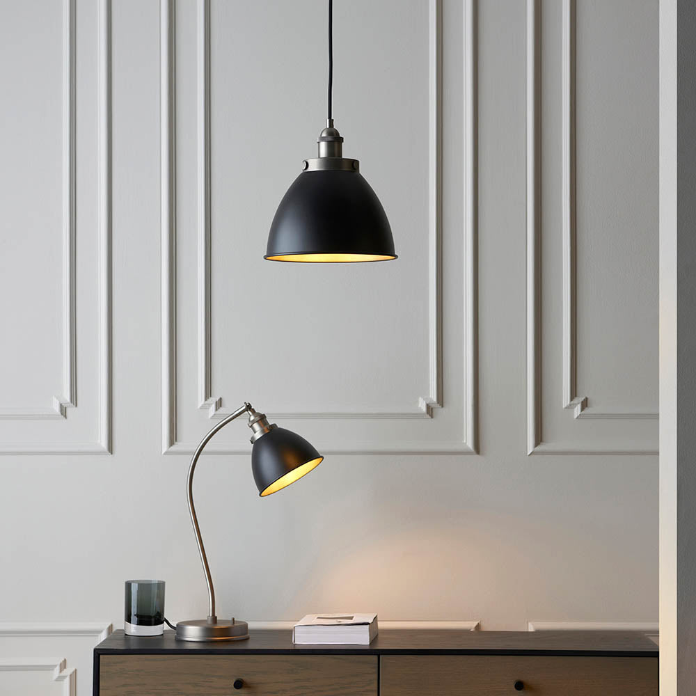 Endon Bramdale small pendant in matt black with aged pewter detailing, shown with a matching table lamp on a wooden sideboard against panelled grey walls.