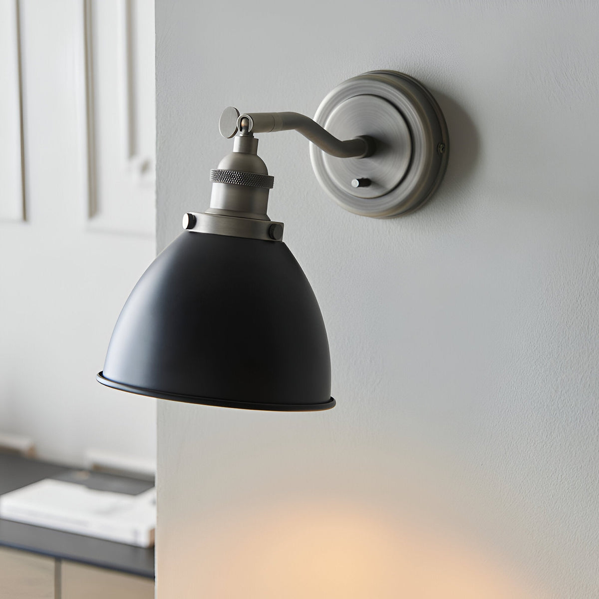 Endon Bramdale industrial wall light with adjustable knuckle, matt black dome shade and aged pewter fitting, mounted on a light grey wall.