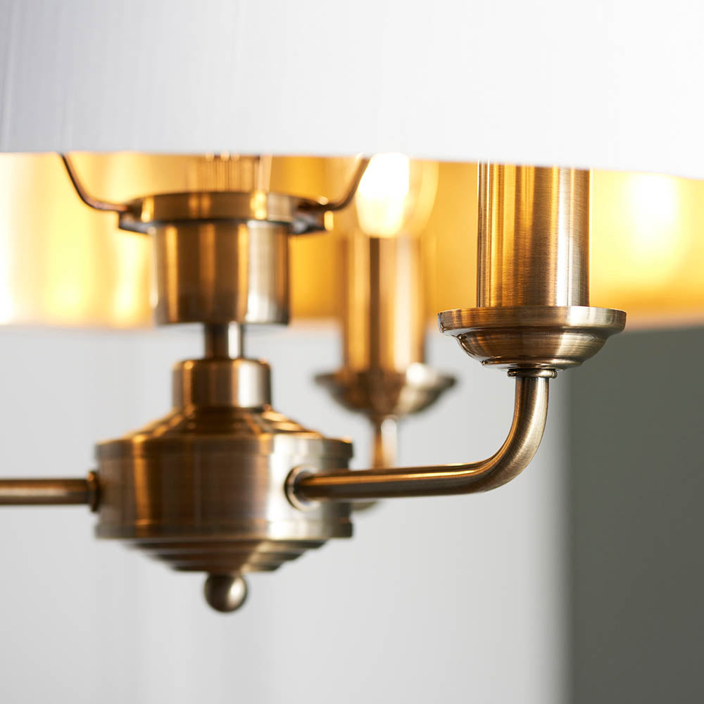 Close-up of Endon Brenley 3 Light Pendant showing antique brass arms, central finial and gold-lined white fabric shade with an E14 lamp visible.