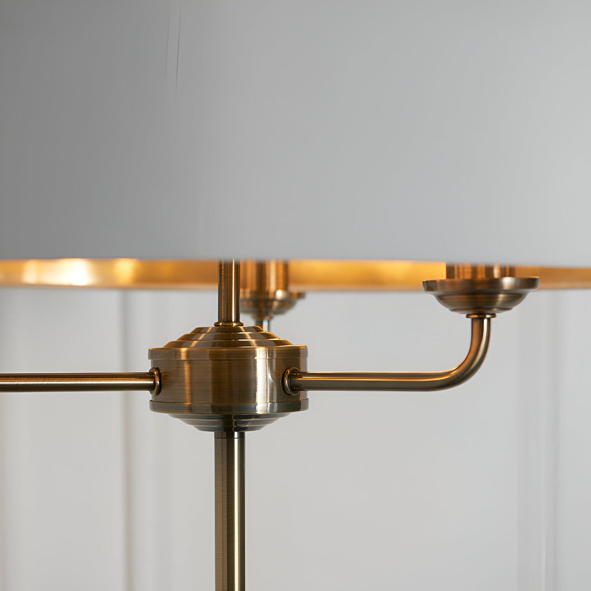 Close-up of the Endon Brenley 3 Light Floor Lamp showing the antique brass central hub, three curved arms, and gold-lined white fabric shade.