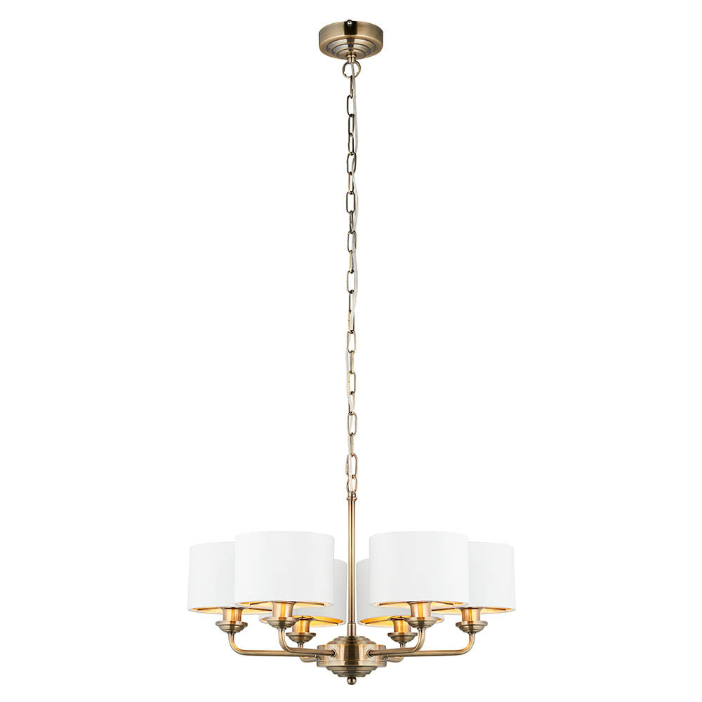 Brenley V2 6-light pendant with antique brass metal arms and chain, white fabric drum shades on each arm, shown on a plain white background.