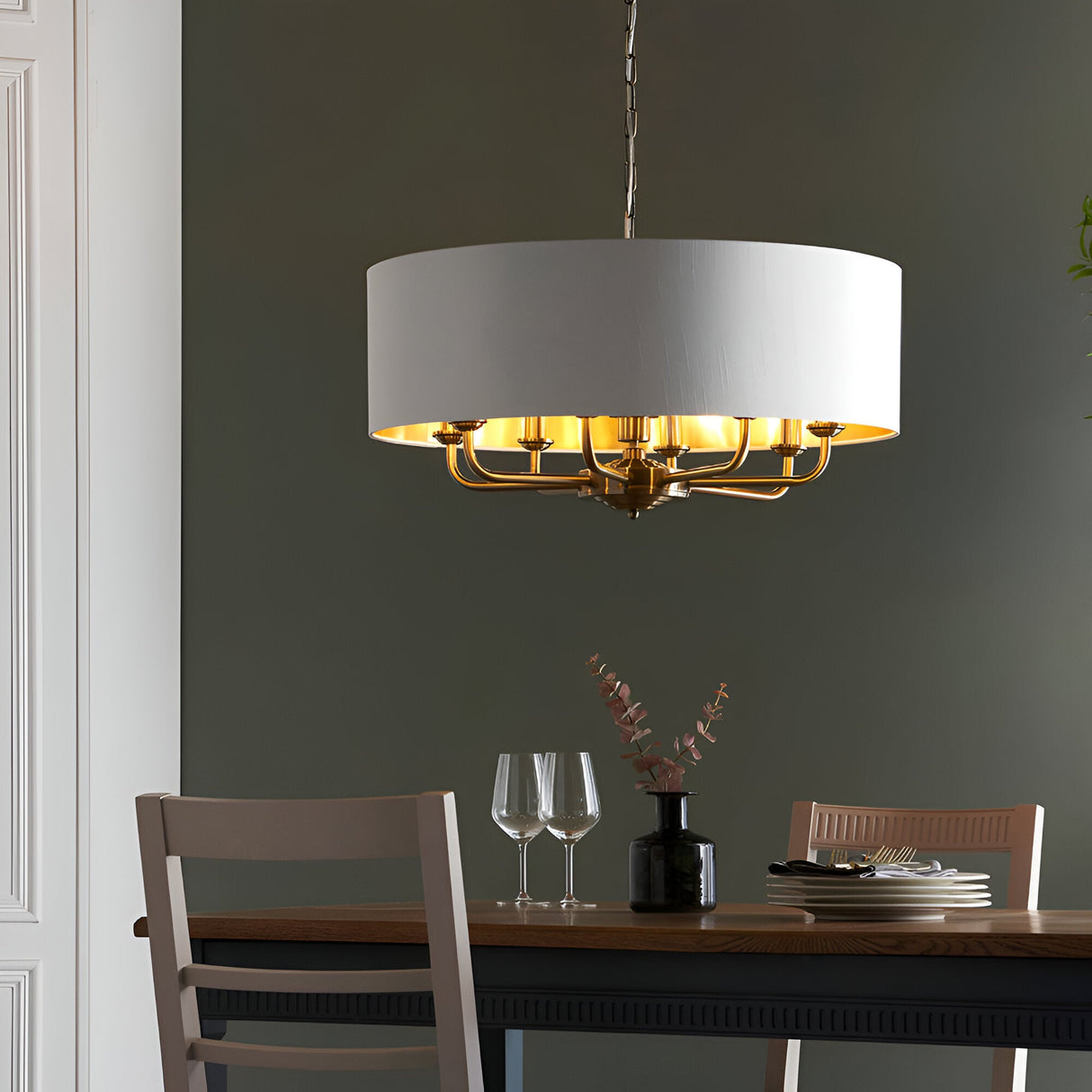 Endon Brenley 8 light pendant with white drum shade and gold-lined interior on a brass multi-arm frame, hanging above a wooden dining table.