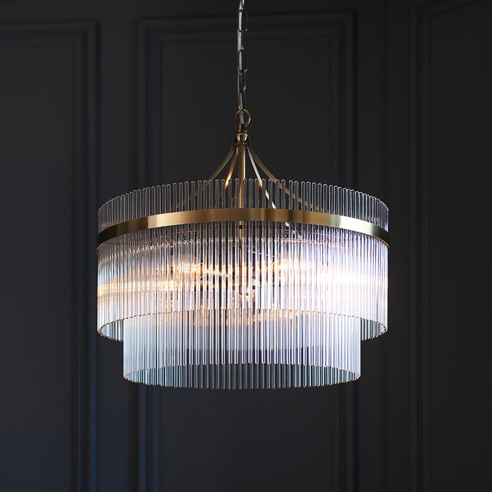 Endon Beaumont 5 Light Pendant in brass, a two-tier chandelier-style fitting with clear glass rods on a height-adjustable chain, shown against dark panelling.