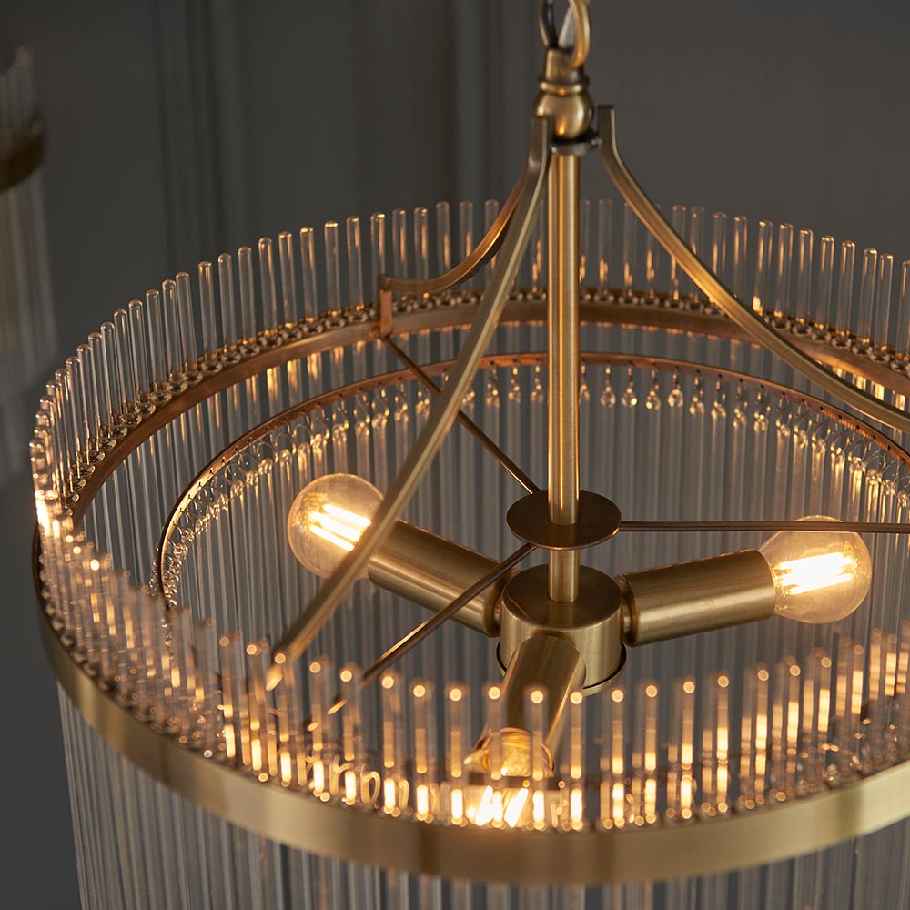 Close-up of the Endon Beaumont 3 Light Pendant in brass, showing three E14 lamp holders on a central hub framed by clear glass rods in a circular drum.
