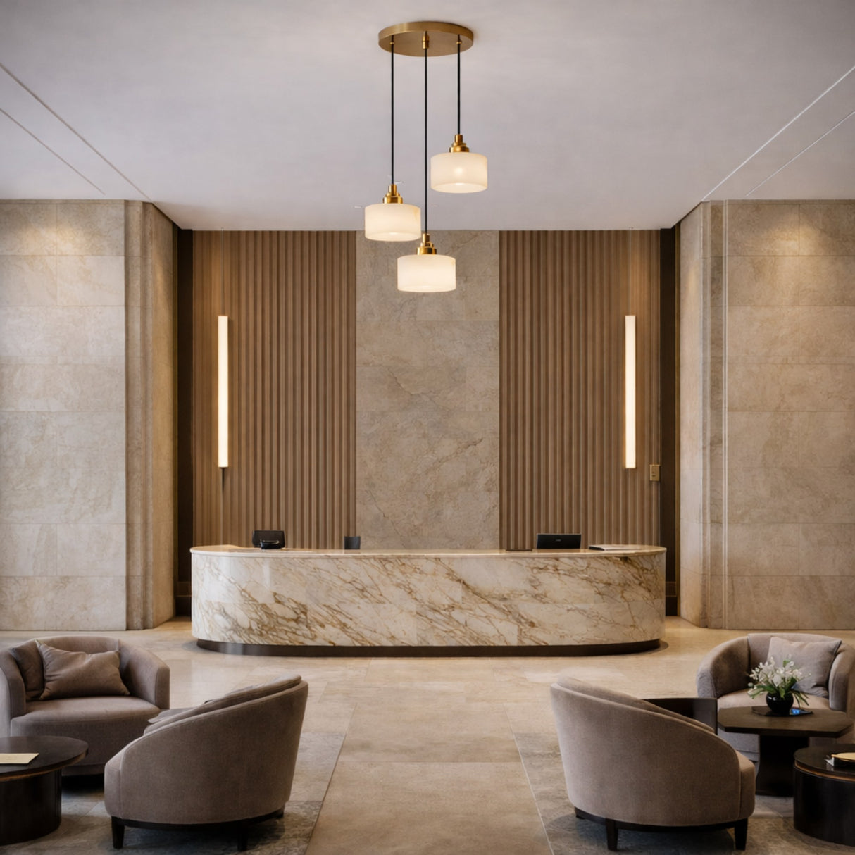 A modern hotel lobby with marble reception, beige stone walls, vertical wood paneling, Brinex 3 Light Cluster Alabaster Pendant Light in soft white and brushed brass, plus gray armchairs around dark tables for a sleek minimalist look.