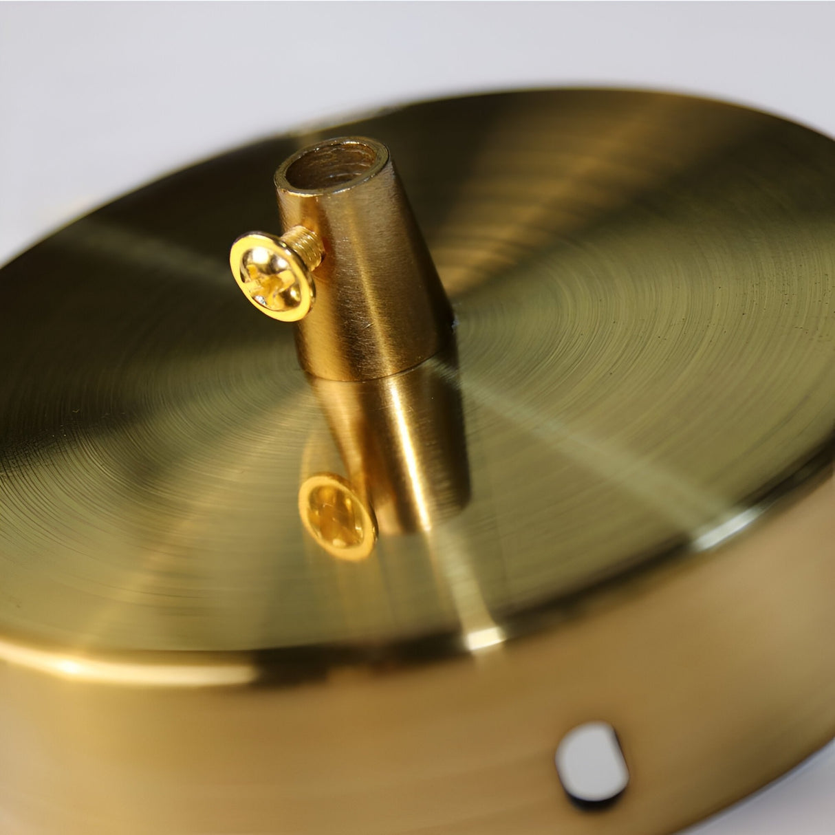 Close-up of a round, gold-colored metal fixture with concentric patterns and threaded screw, designed for an E27 socket. This component is part of the Arc Pendant Light - Gold & White, perfect for modern interiors.