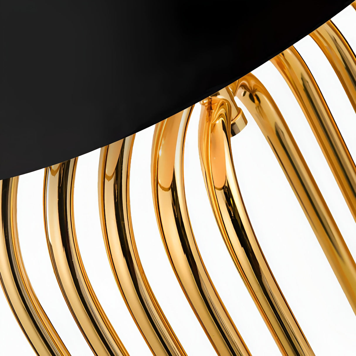 Close-up of shiny, curved gold metal bars from the Ascot 4 Light Large Table Lamp - Black & Gold, arranged in parallel beneath a smooth black surface, set against a white background.