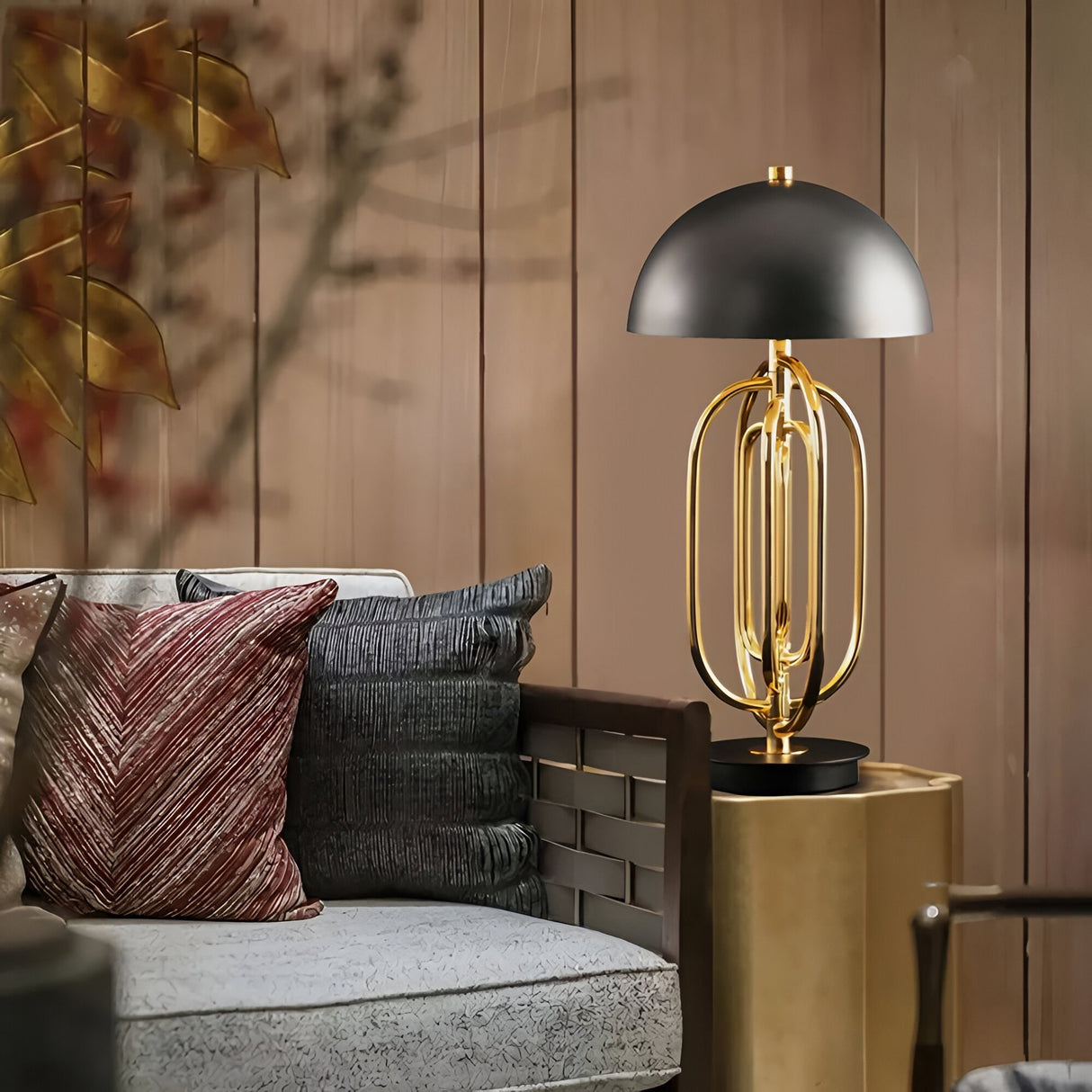A modern living room features a gray sofa, decorative pillows, and the Ascot 4 Light Large Table Lamp in Black & Gold with its dome shade on a side table, adding statement lighting against wooden paneled walls.