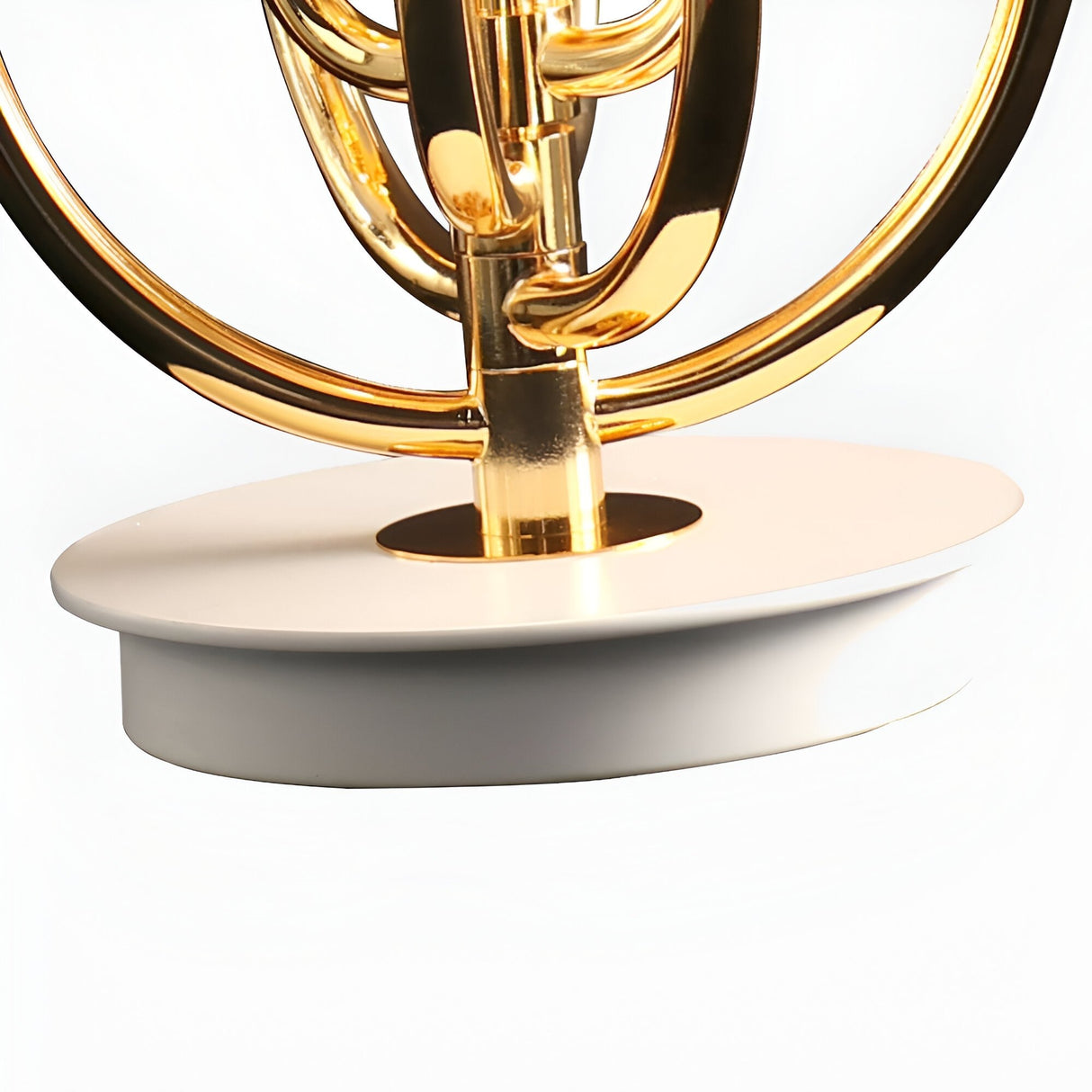 A close-up of the Ascot 4 Light Large Table Lamp featuring a shiny gold-finished metal body with adjustable arcs, mounted on a smooth oval white base, displayed against a plain background.