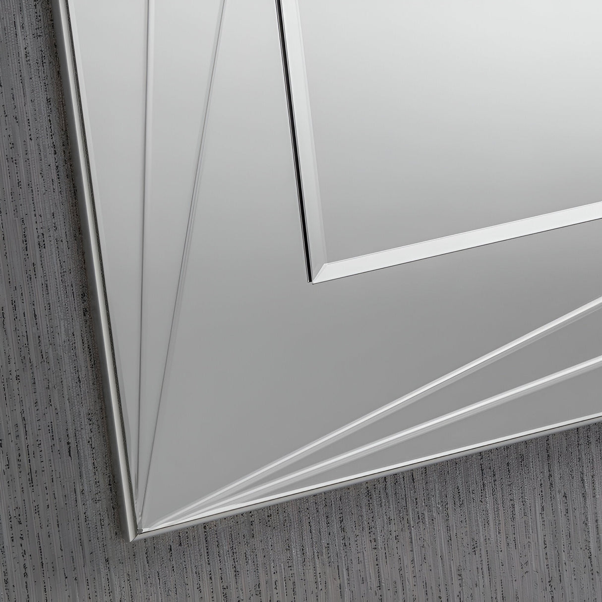 A close-up shows the Polaris Rectangle Wall Mirror- 108x77cm, featuring complex geometric shapes with numerous beveled edges and lines. It is positioned against a textured gray wall, while its minimalist frame accentuates a modern and angular style, bringing an elegant and sophisticated appearance to contemporary decor.