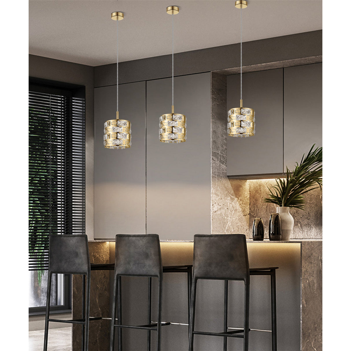 Three Impex Solara crystal pendant lights in gold hung in a row above a kitchen island bar with dark stools and grey cabinetry.