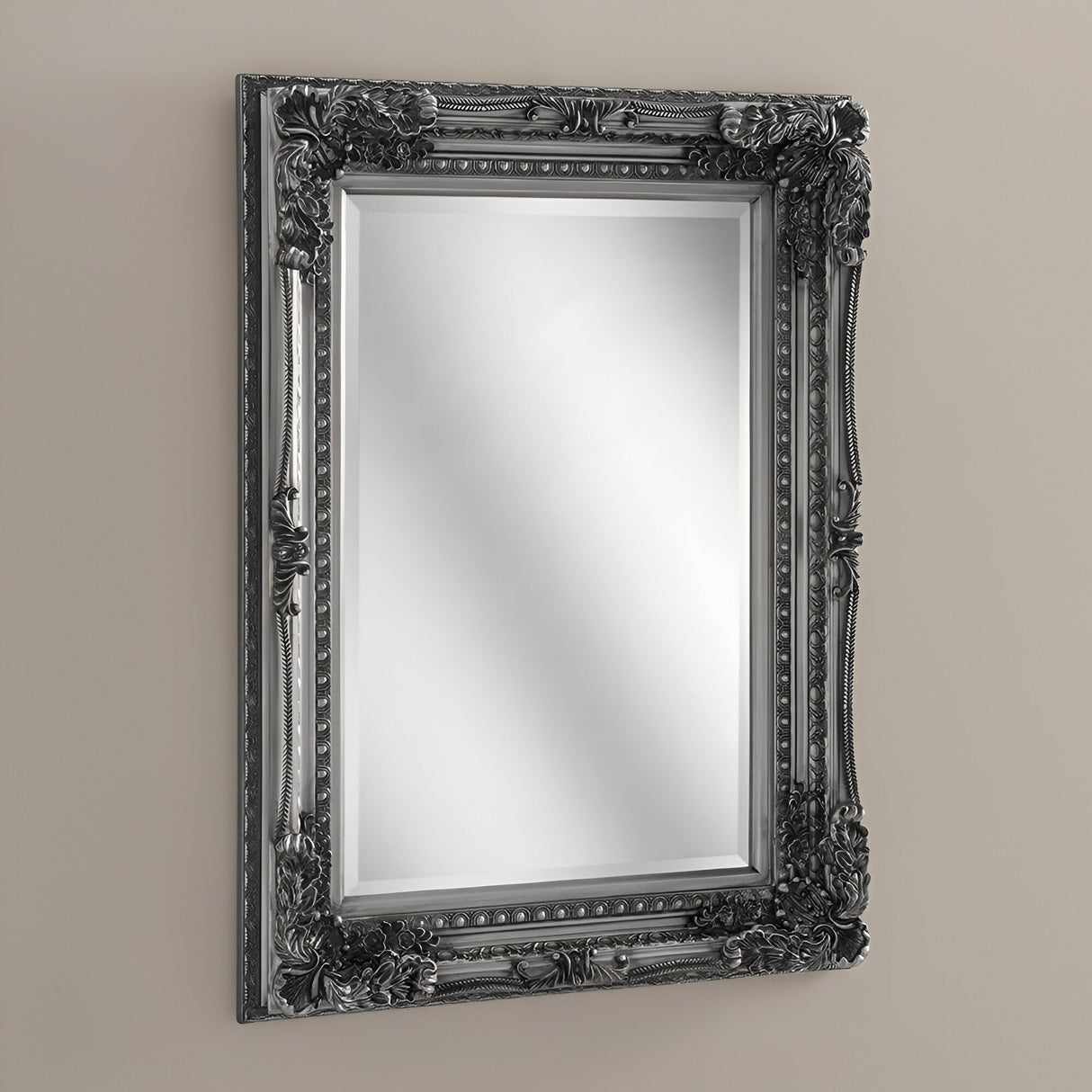 The Chantelle Rectangle Wall Mirror Silver (119x89cm), with its intricate dark frame adorned with floral and decorative carvings, adds elegance to any space when hung on a light-colored wall.