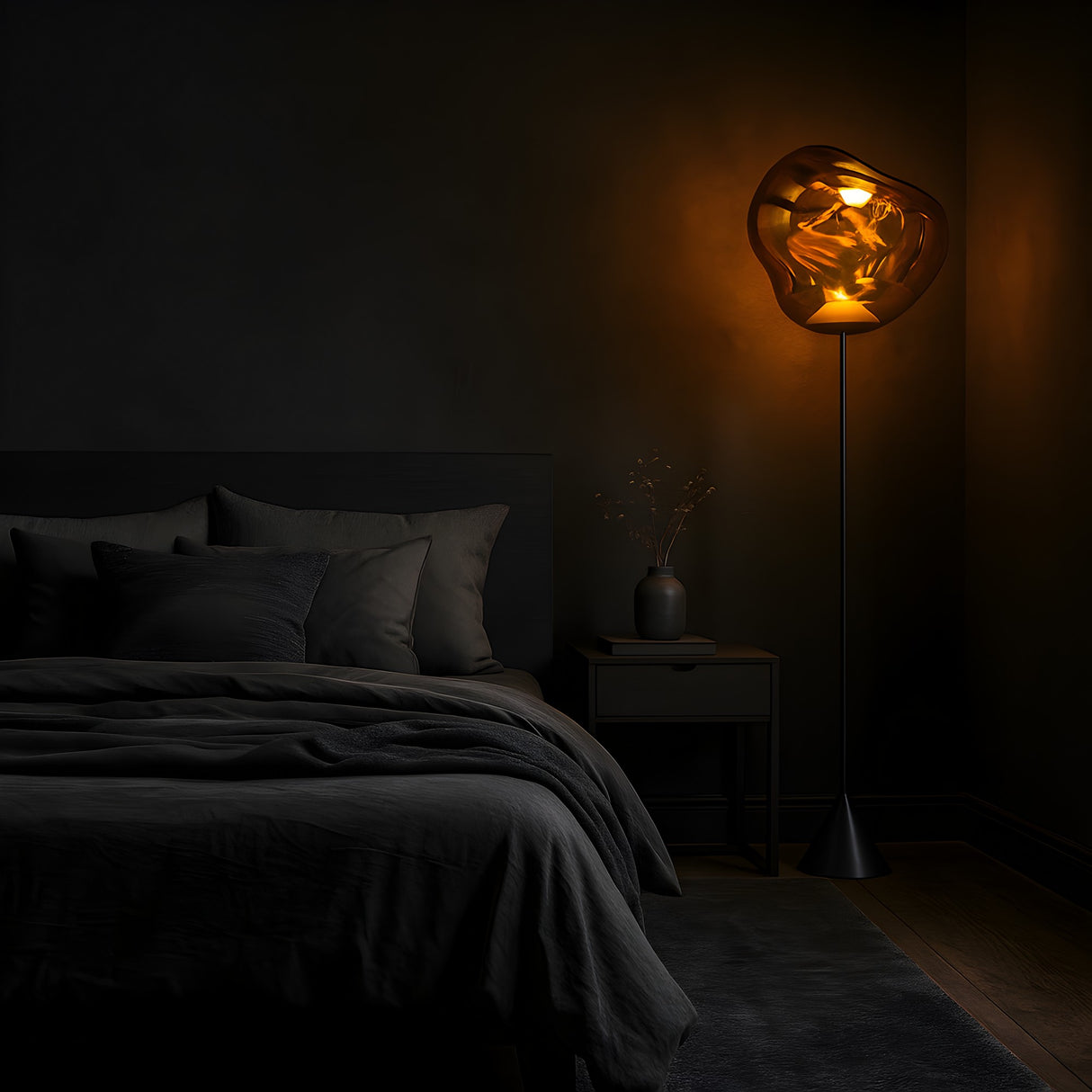 A dimly lit bedroom with dark walls and bedding is illuminated by the Lava LED Floor Lamp - Copper, placed beside a nightstand with a vase of branches, creating cozy ambient lighting and a moody atmosphere.