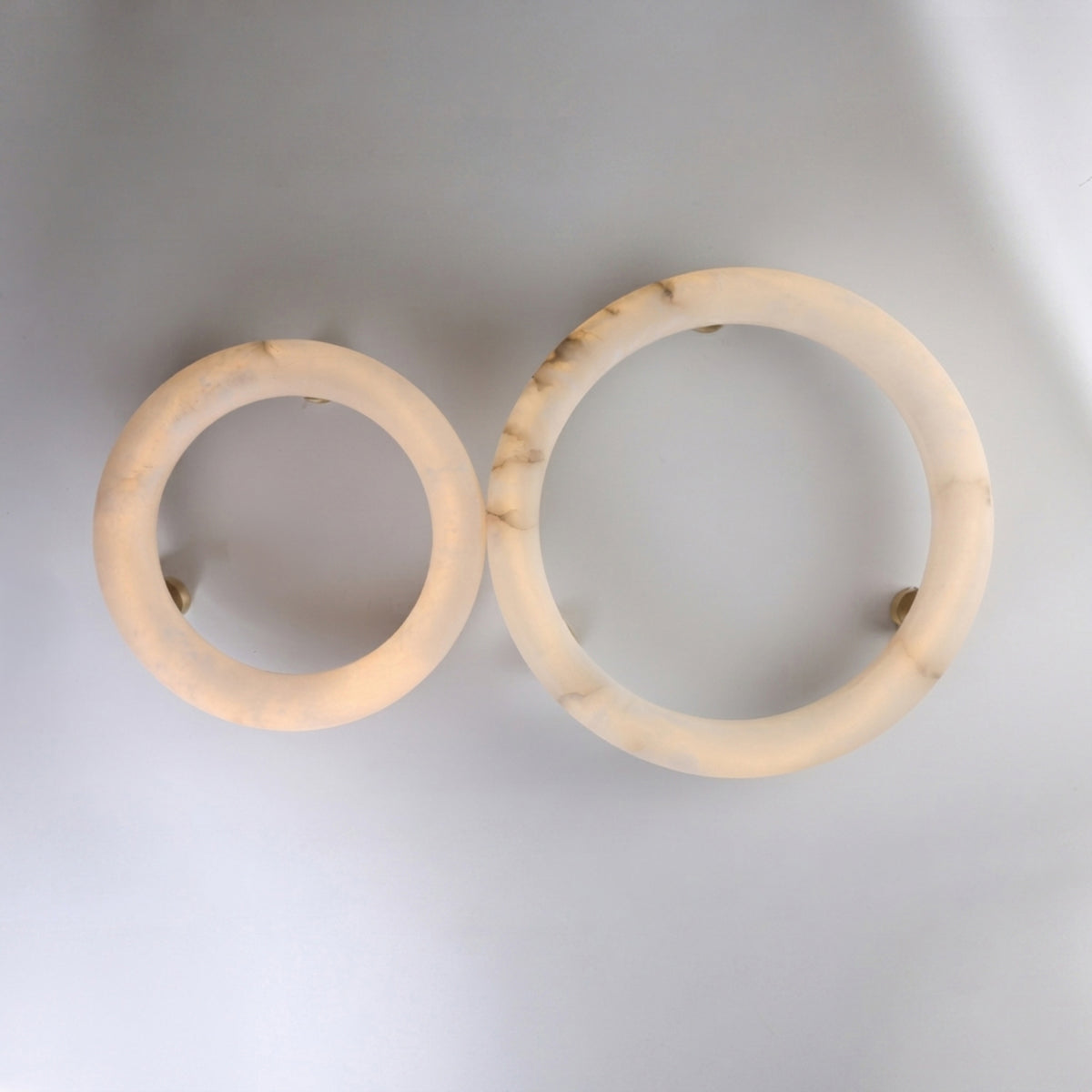 Two round alabaster semi-flush ceiling lights, Orbis Extra Large and a smaller version, shown side by side with brass mounts on a plain white background.